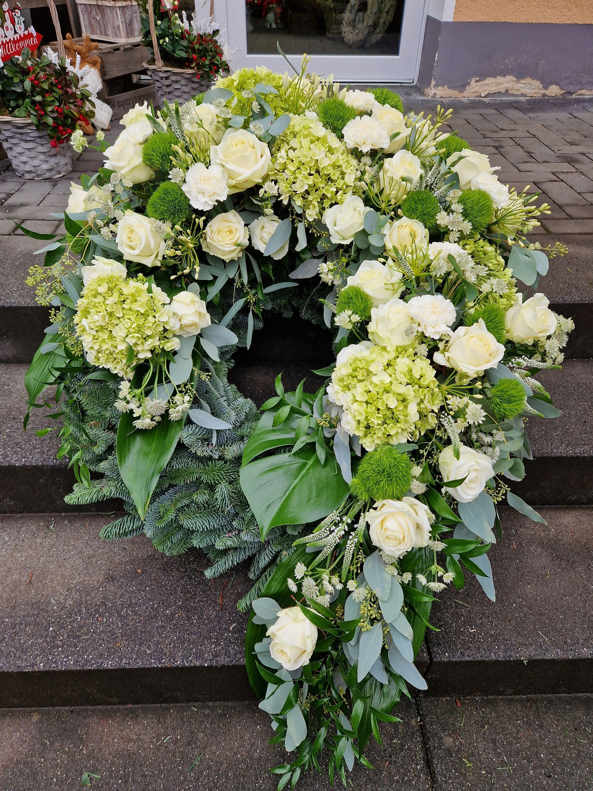 Ein Kranz aus weißen und grünen Blumen sitzt auf einer Treppe