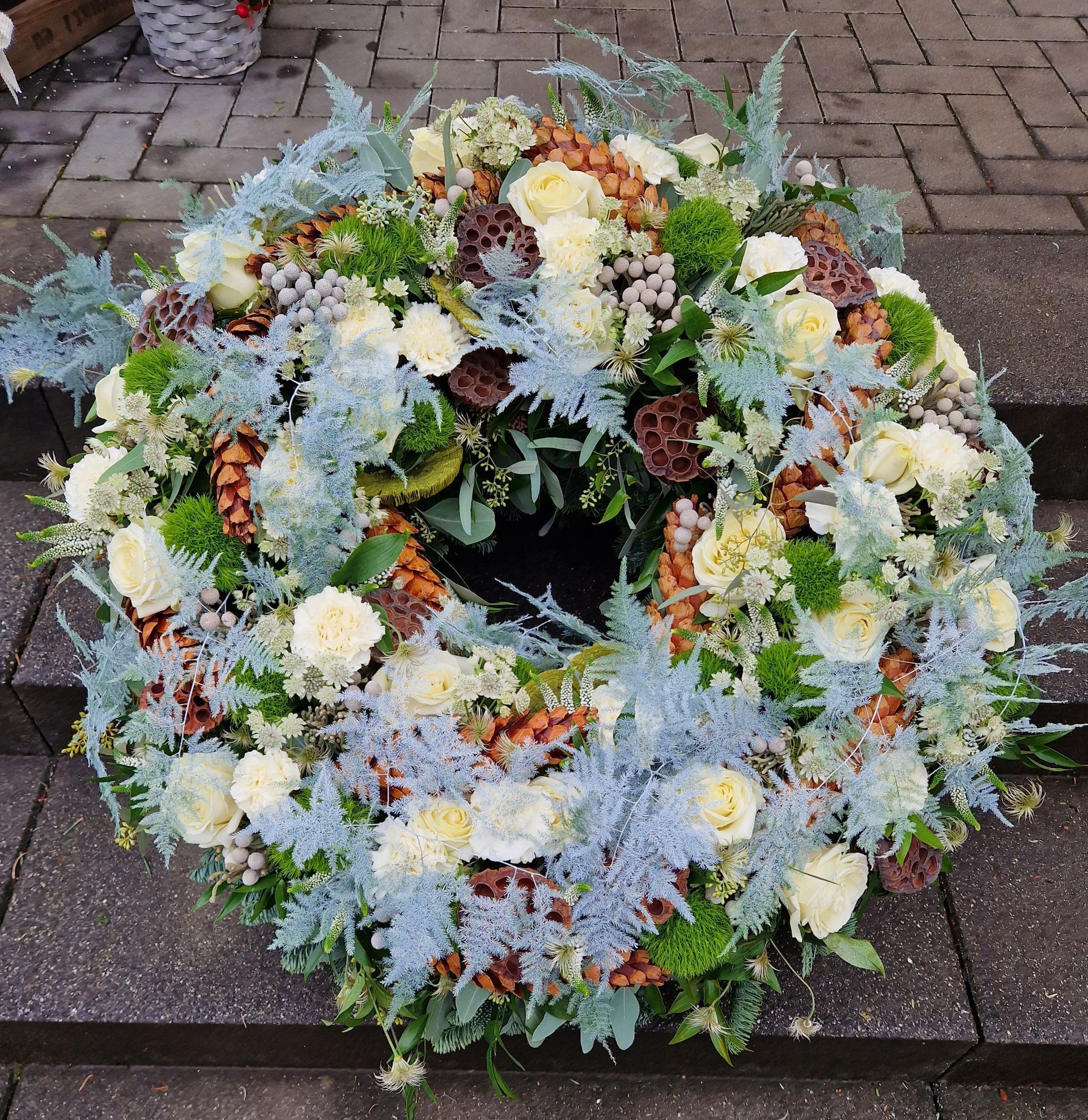 Blumenhof Eymold - Nahaufnahme eines Sarges mit Urne und Blumenkranz aus roten Rosen