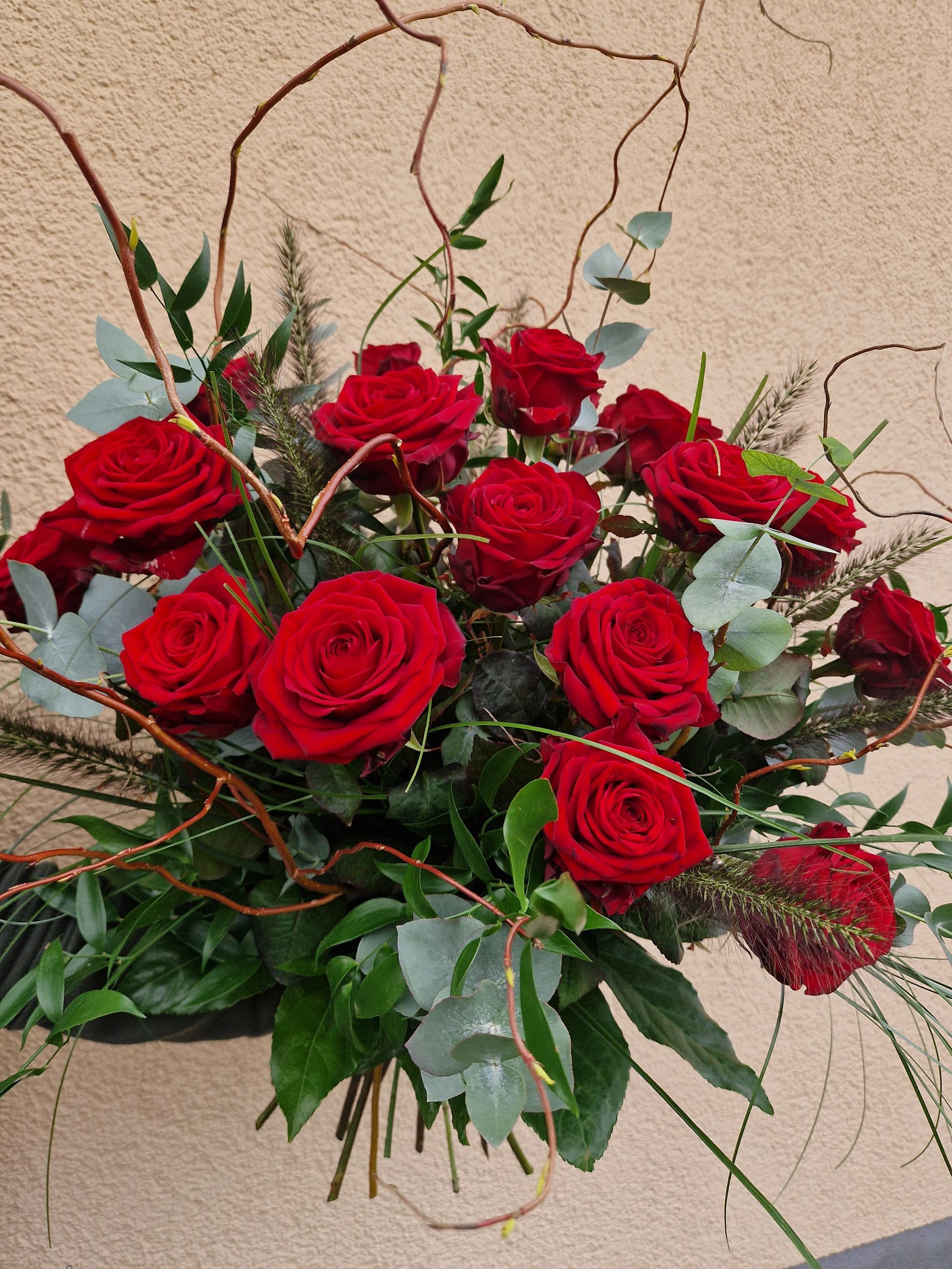 Ein Strauß roter Rosen und Grün auf einem Tisch