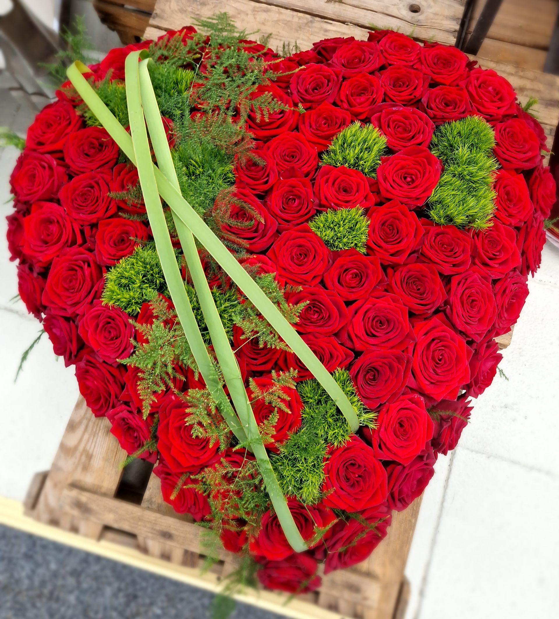 Ein herzförmiges Arrangement aus roten Rosen und Grün