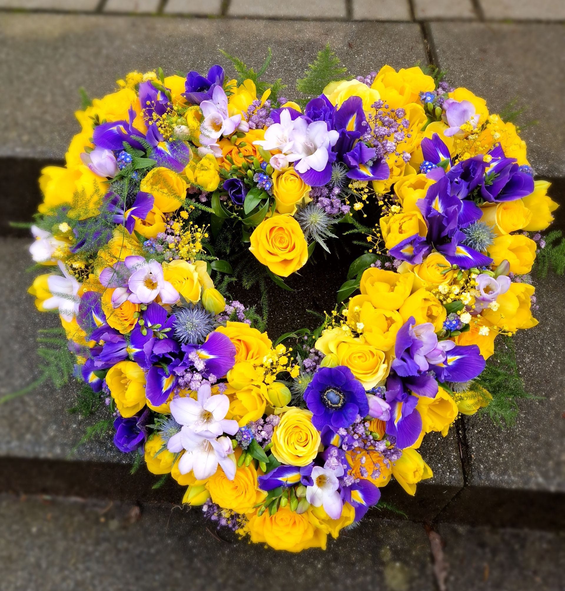 Ein herzförmiger Kranz aus gelben und lila Blumen