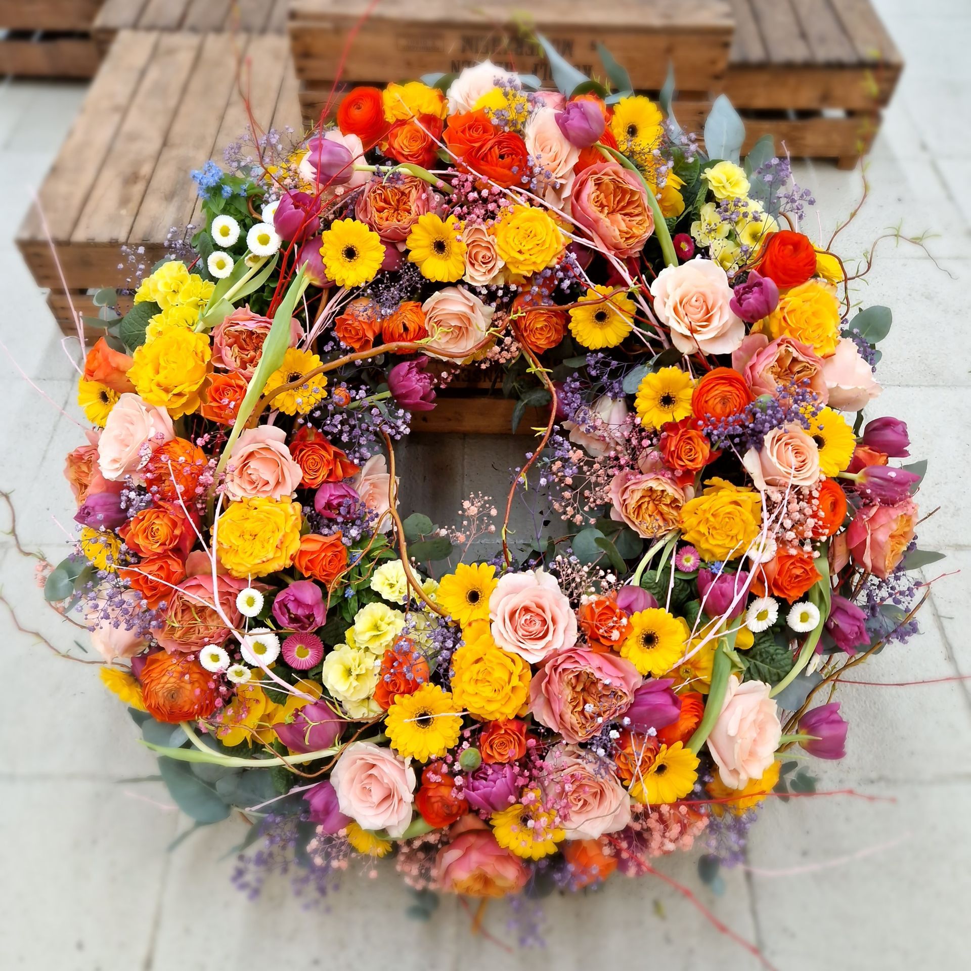 Ein Kranz aus bunten Blumen liegt auf einem Bürgersteig