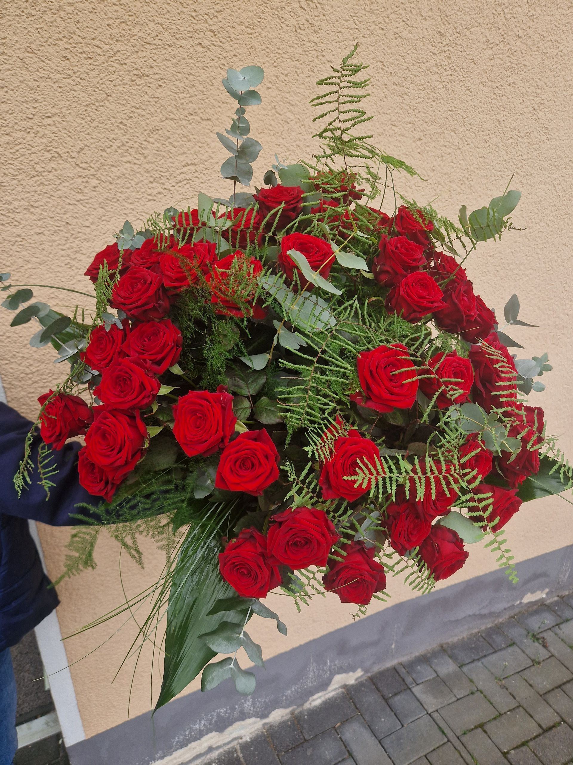 Eine Person hält einen großen Strauß roter Rosen