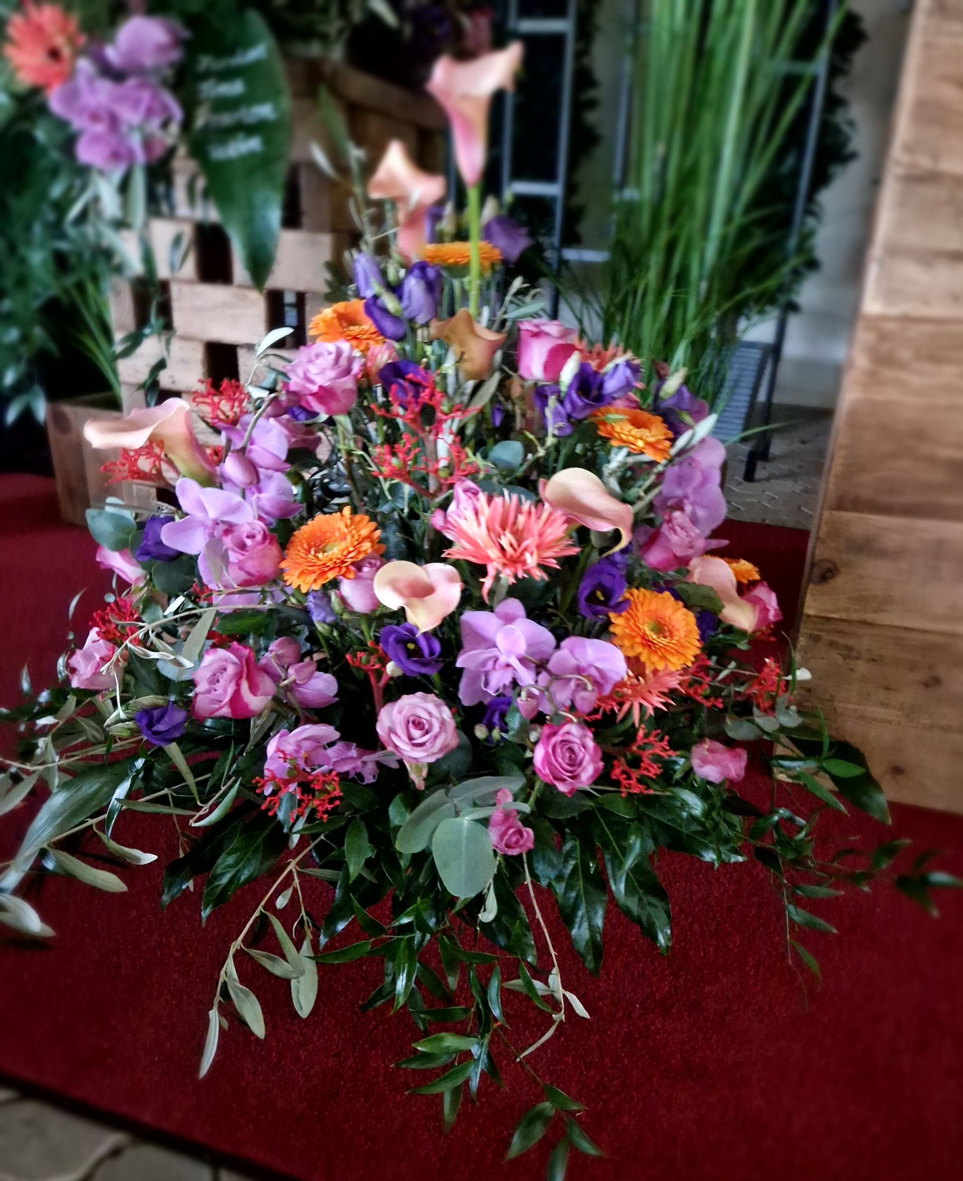 Ein großer Blumenstrauß steht auf einem roten Teppich.