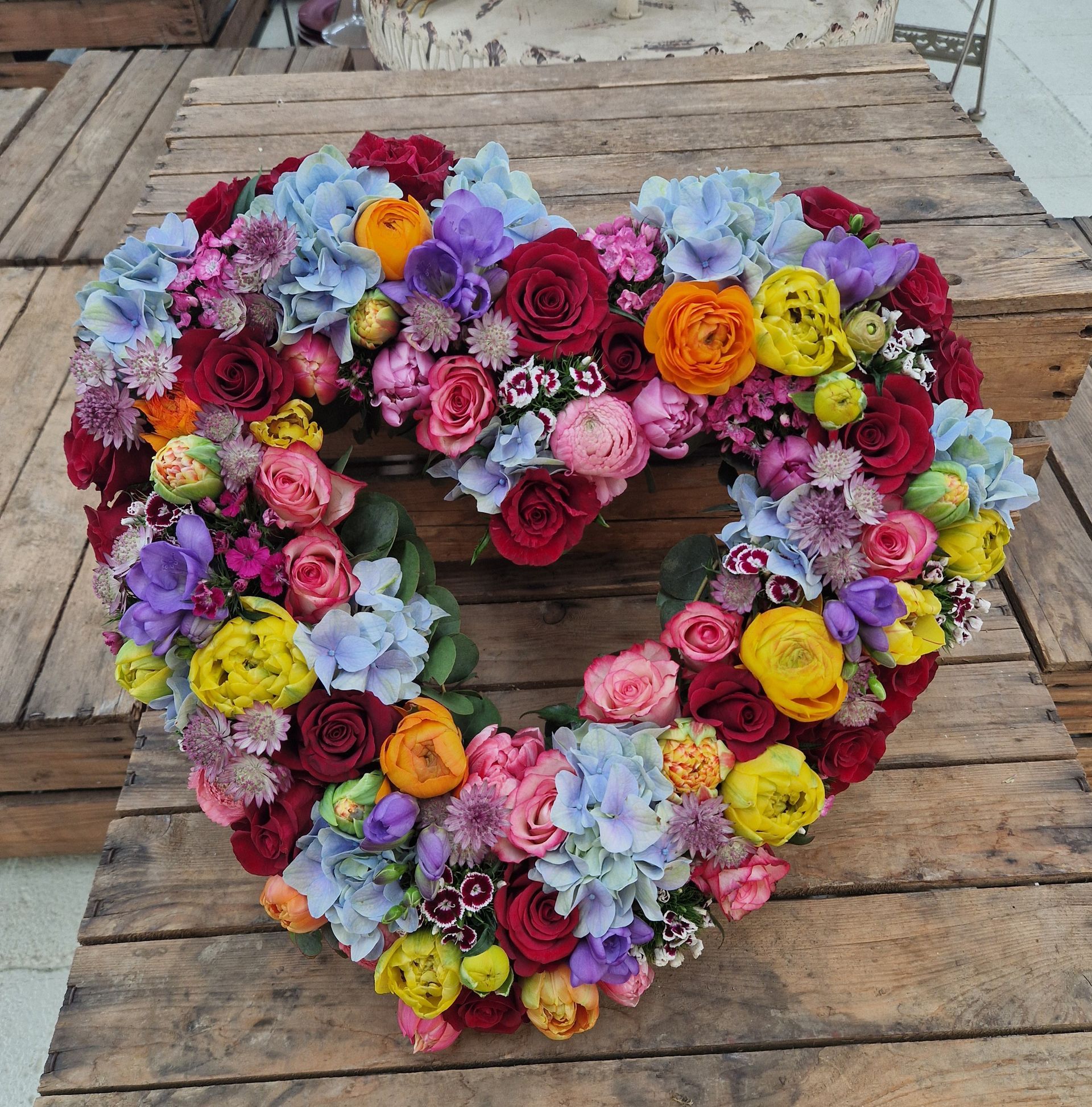 Ein herzförmiger Blumenkranz auf einem Holztisch