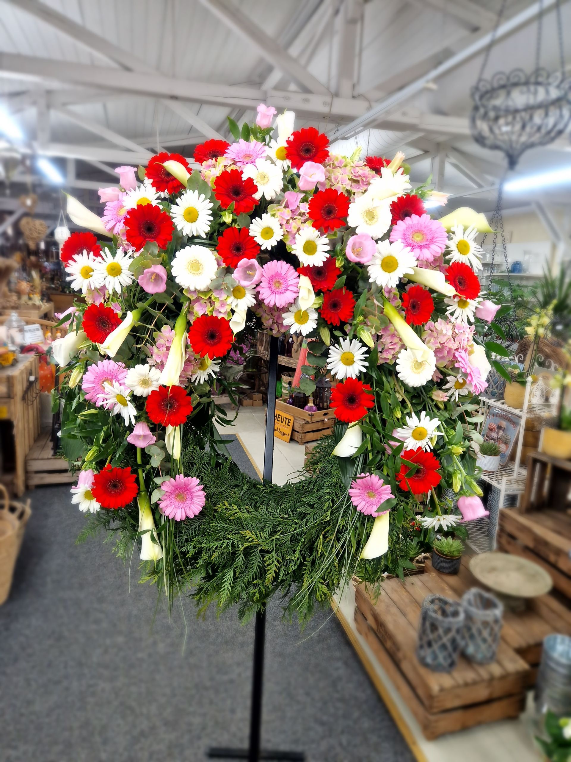 Ein großer Kranz aus roten, rosa und weißen Blumen