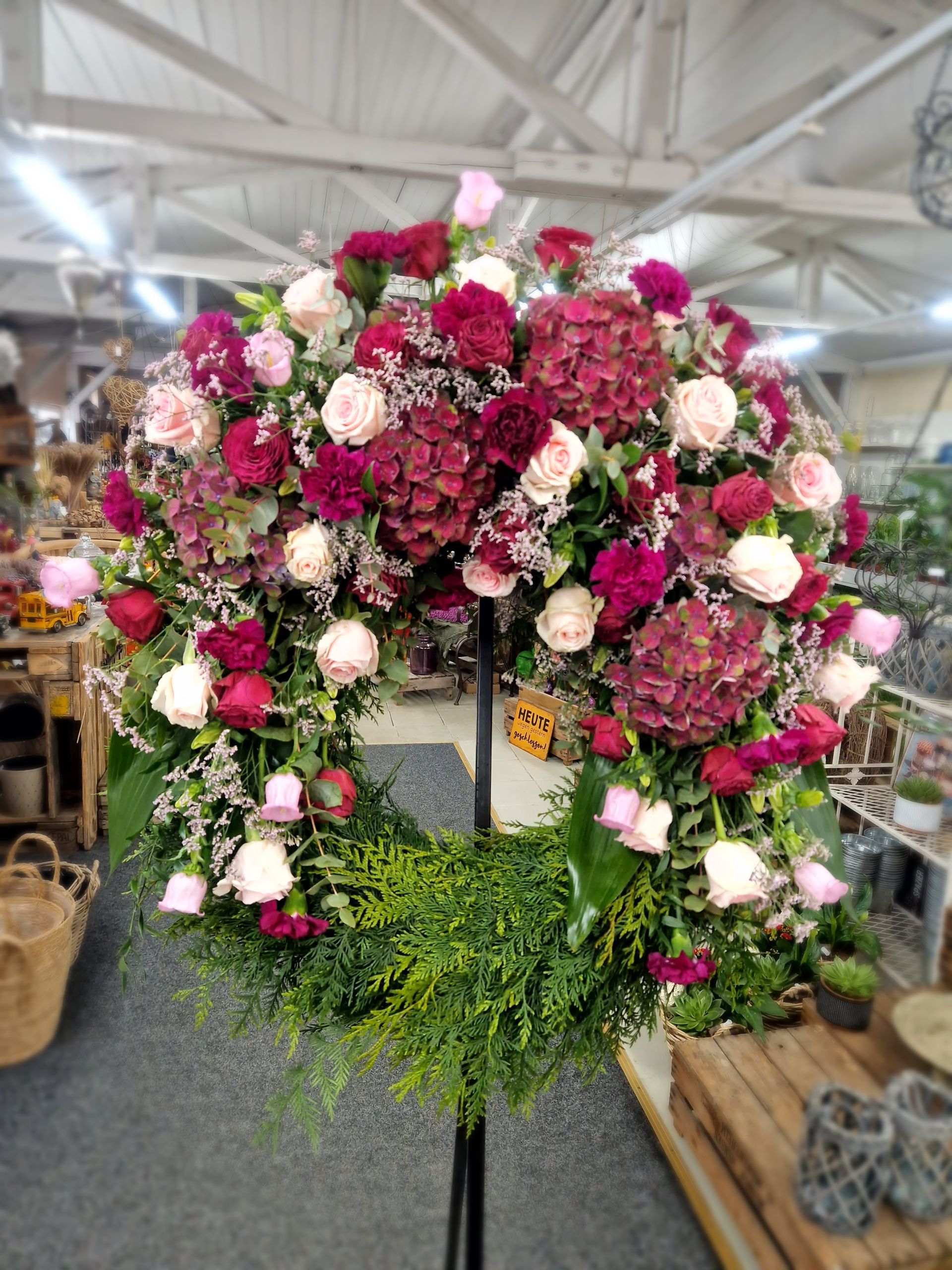 Ein großer Blumenkranz steht auf einem Ständer in einem Geschäft.