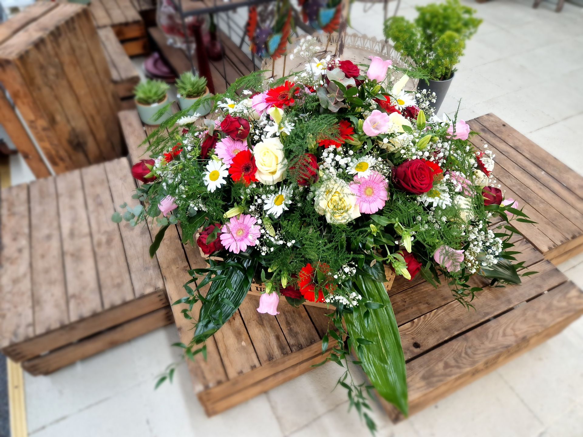 Ein großer Blumenstrauß steht auf einem Holztisch.