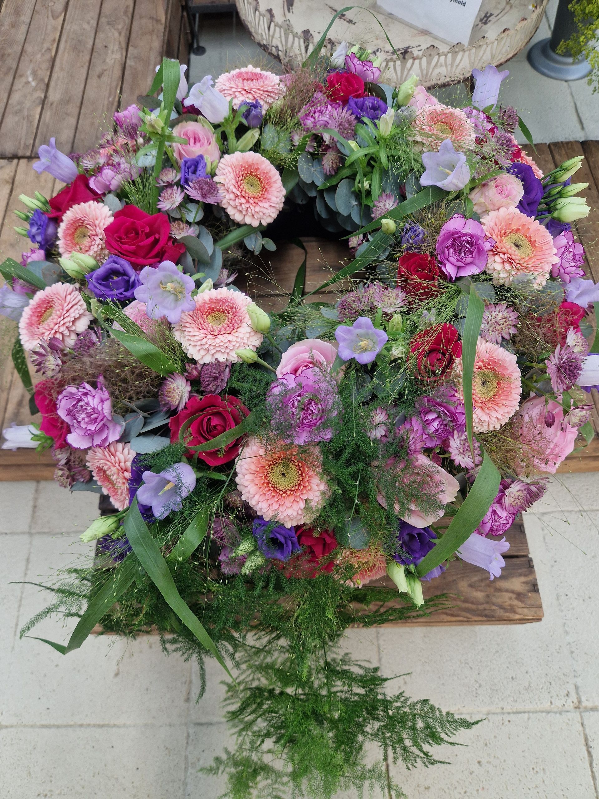 Auf einem Holztisch steht ein Blumenkranz.