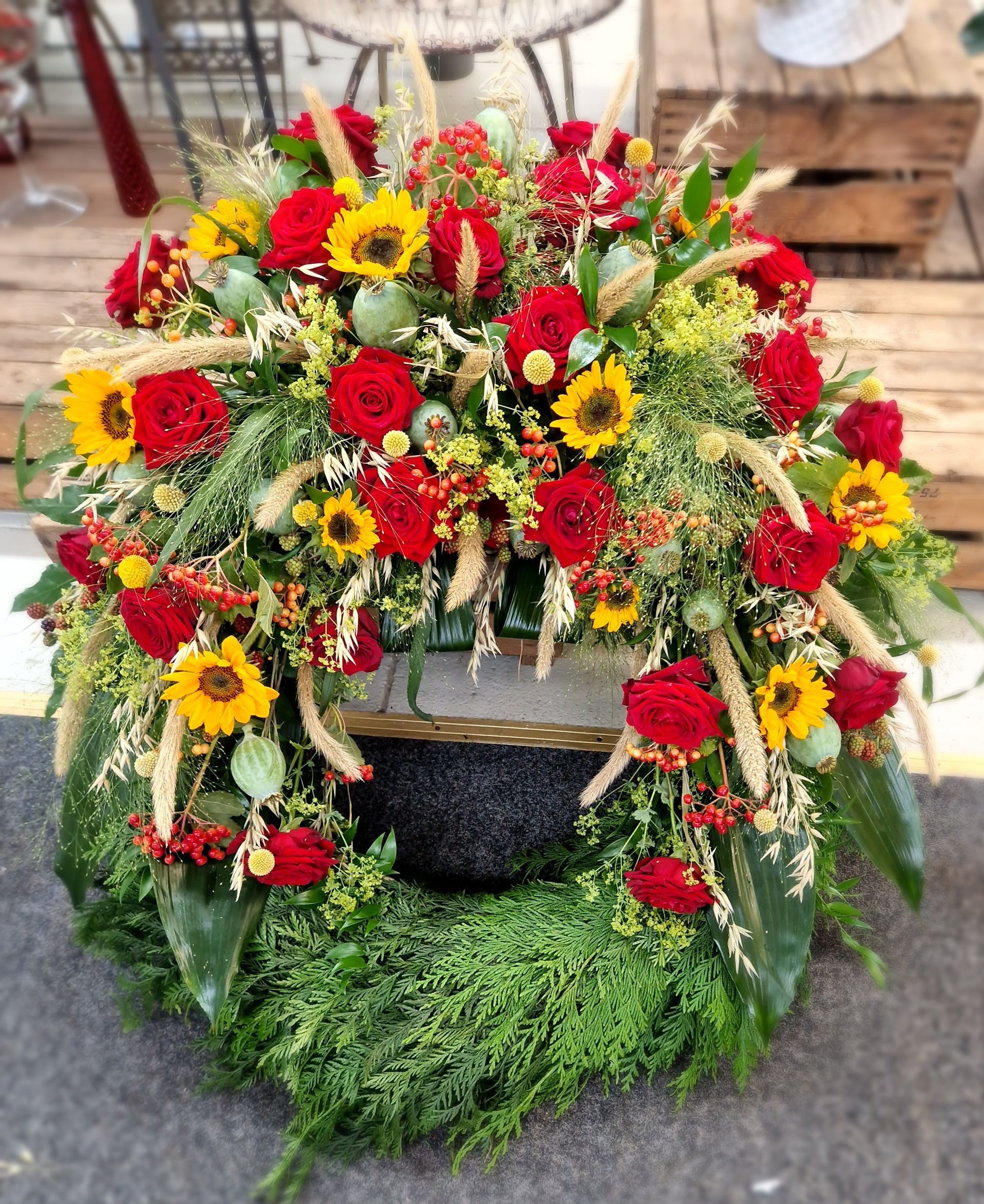 Auf dem Boden liegt ein Kranz aus roten und gelben Blumen.