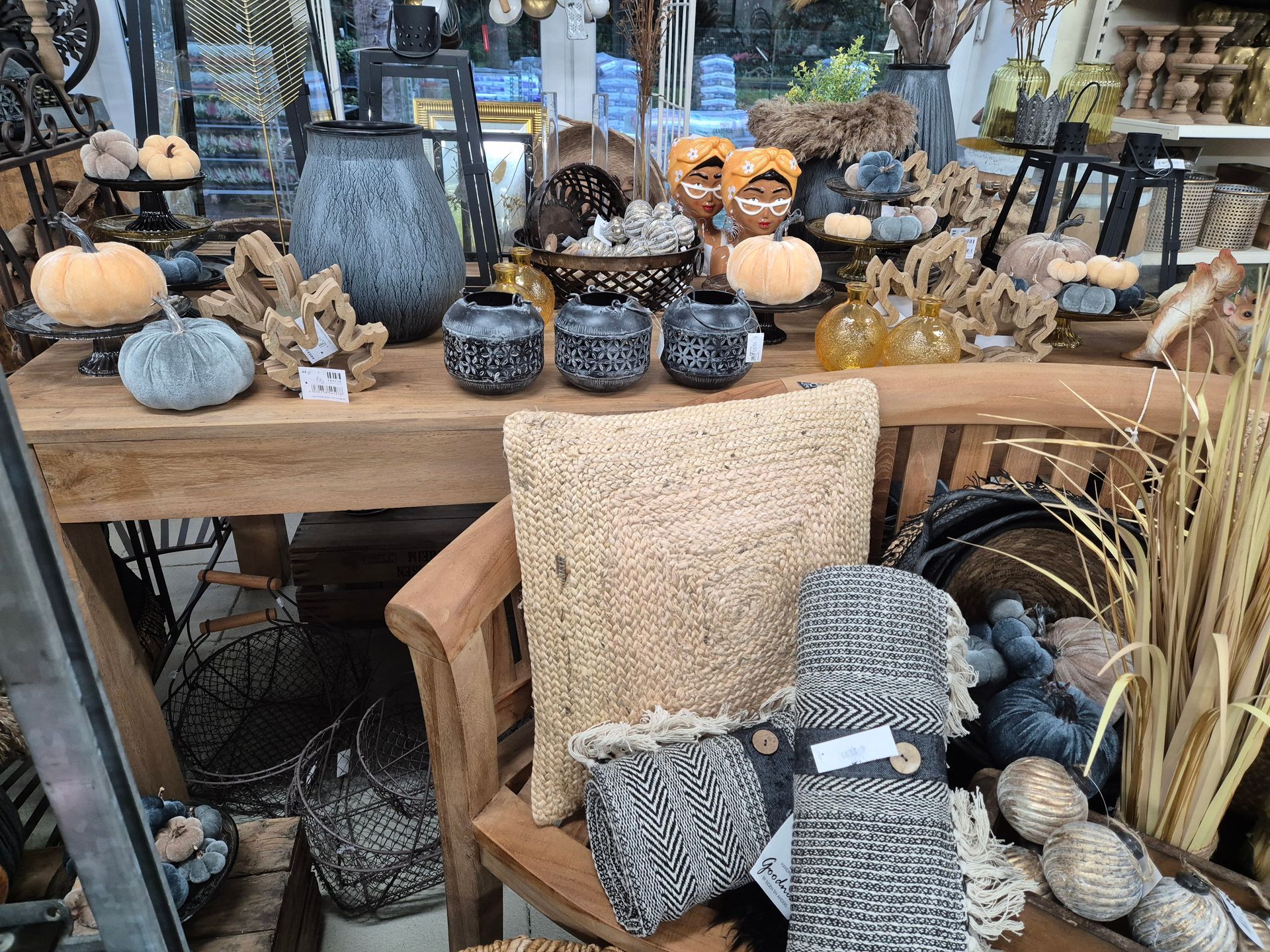 Ein Tisch mit einem Stuhl, Kissen, Kerzen und Kürbissen darauf.