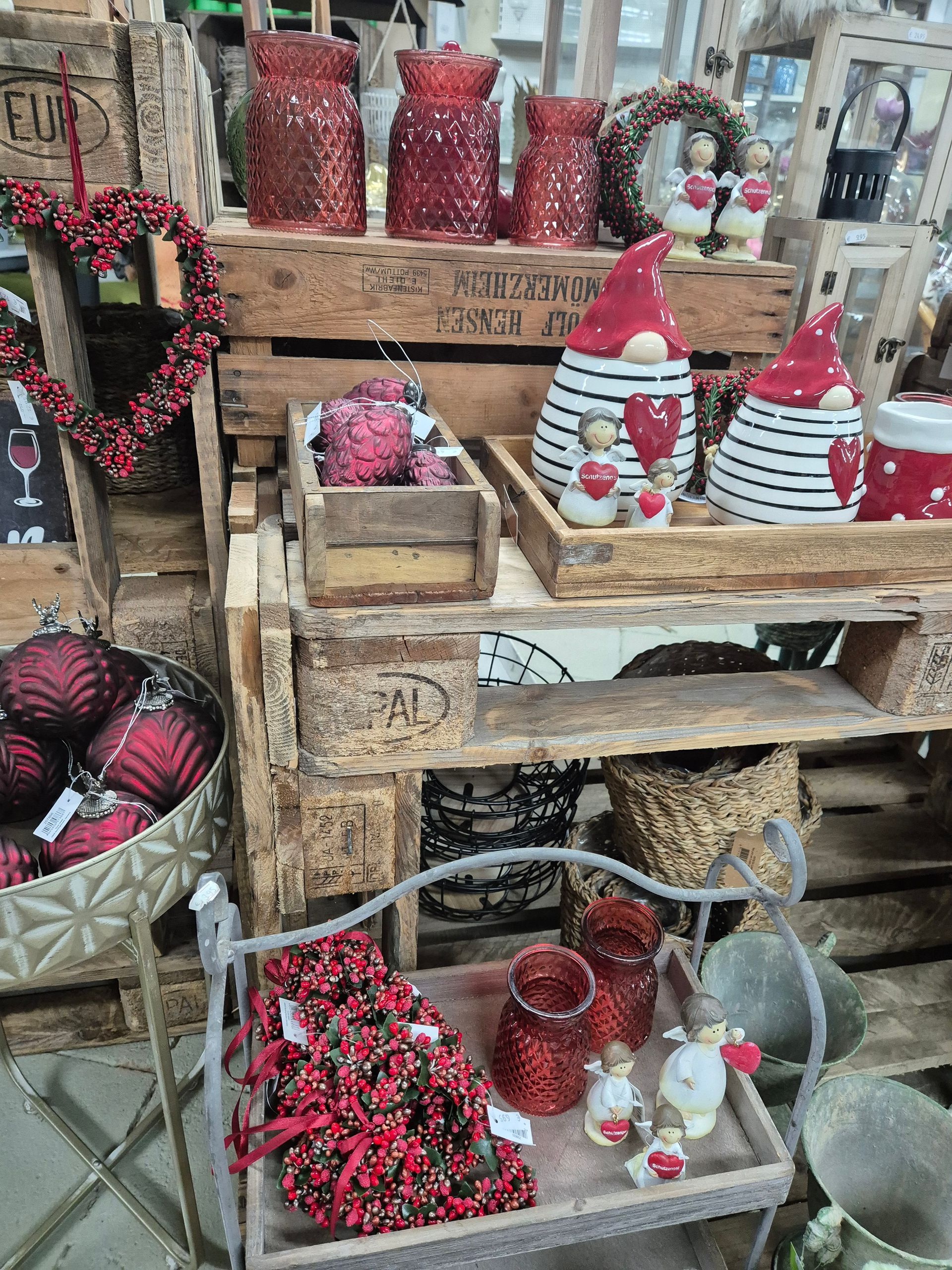 Eine Ausstellung mit Weihnachtsdekorationen auf einem Holzregal in einem Geschäft.