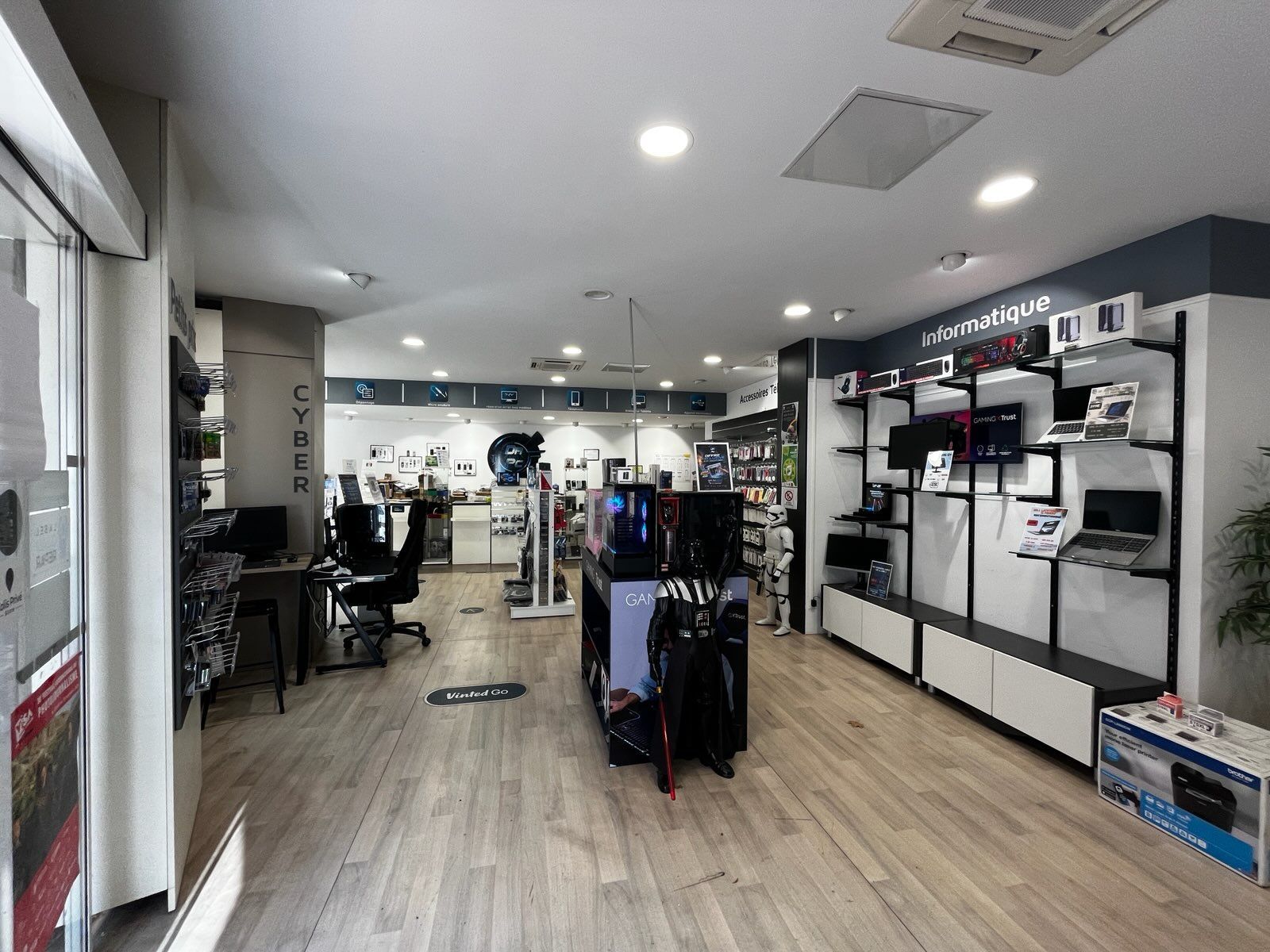 Intérieur lumineux d'un magasin avec étagères d'exposition, appareils électroniques et parquet.