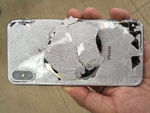 IPhone fissuré avec protection d'écran blanche brisée, tenu d'une main.