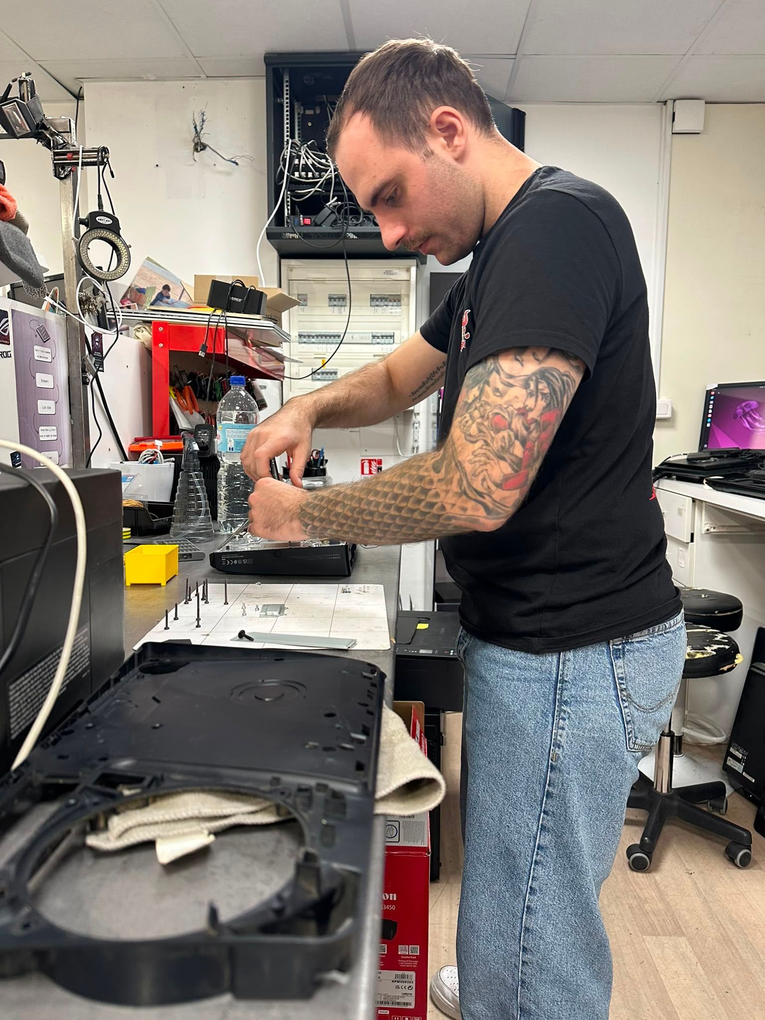 Un technicien répare un appareil sur un établi encombré dans un atelier.