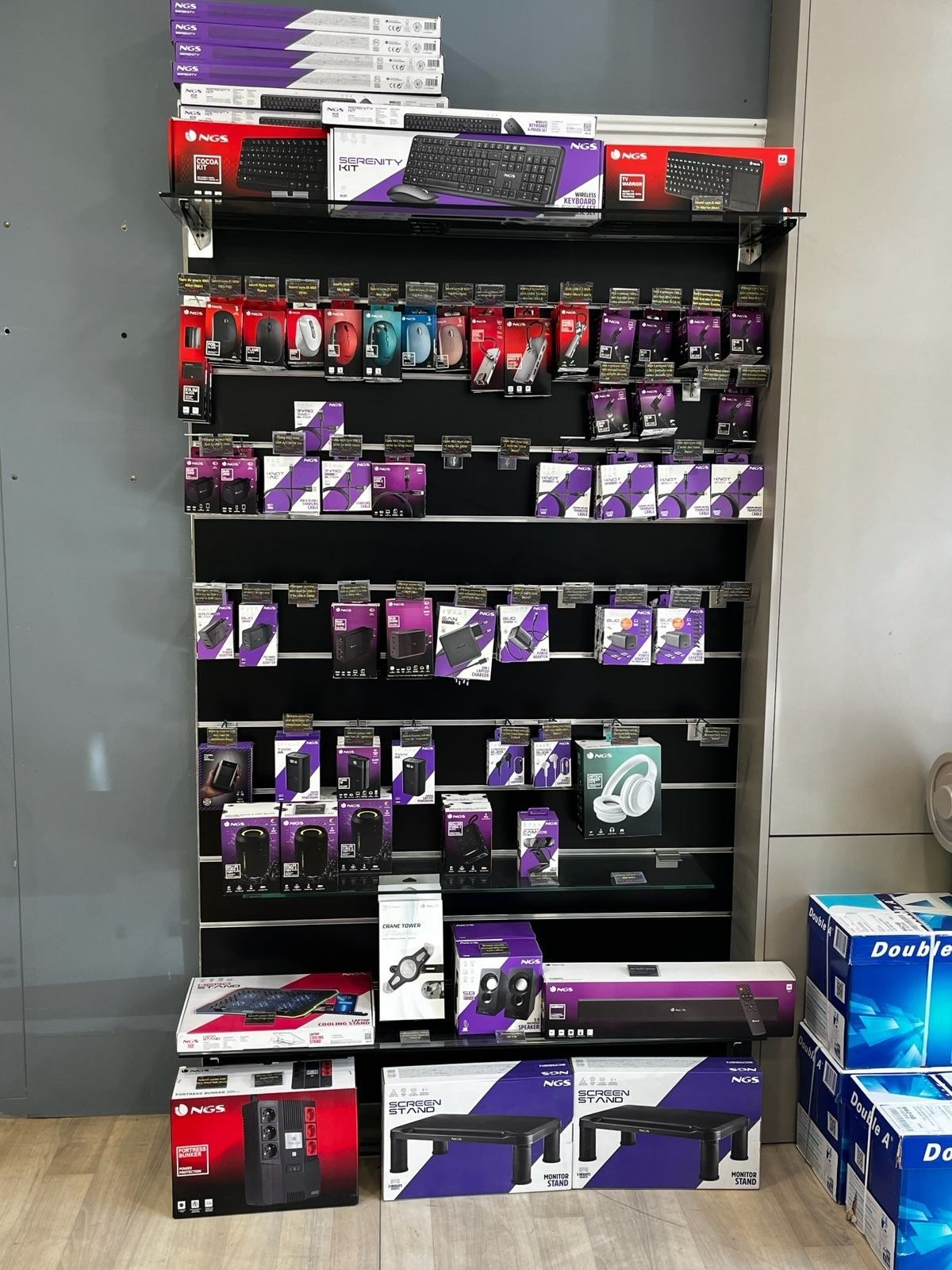 Rayon de présentation en magasin garni d'accessoires informatiques violets et noirs et d'appareils électroniques en boîte.