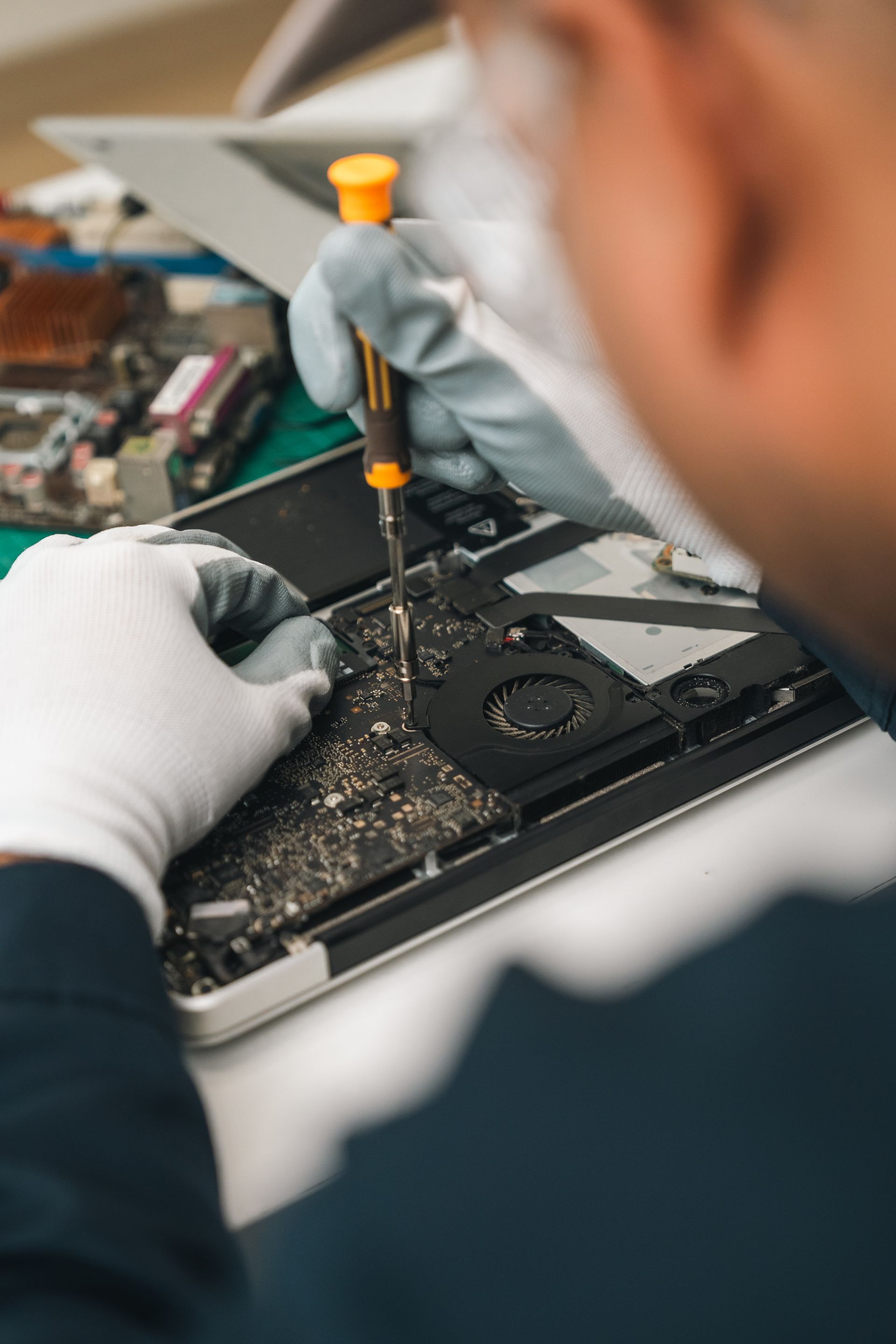Un technicien répare un ordinateur portable ouvert à l'aide d'un tournevis sur un établi.