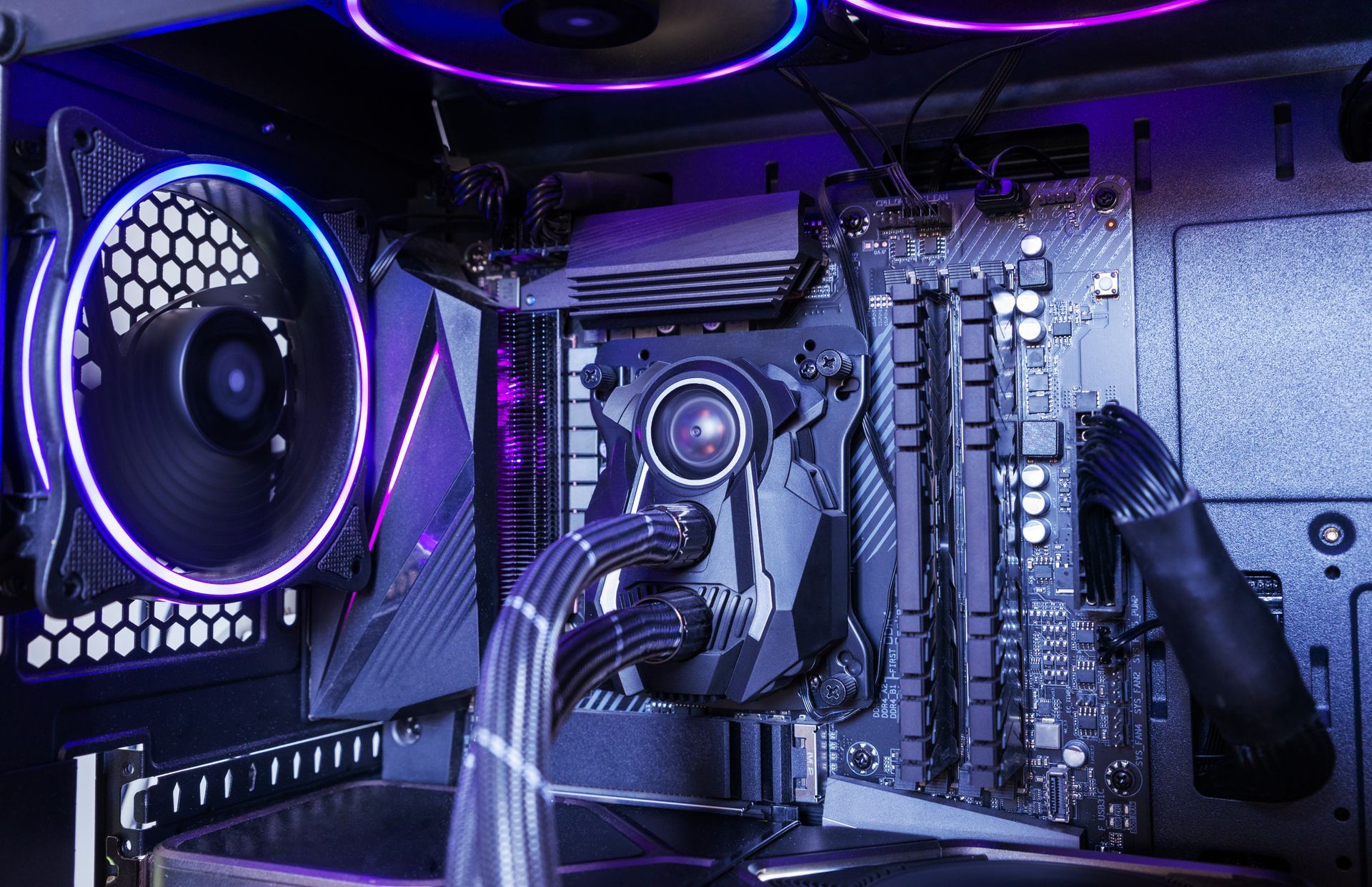 Intérieur d'un PC gaming avec éclairage RGB, ventilateurs violets, carte graphique, carte mère et composants de refroidissement.