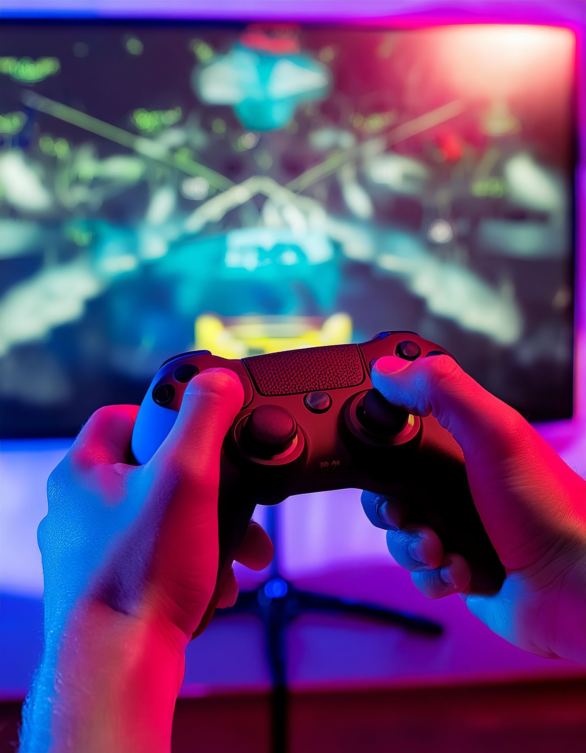 Mains d'un gamer tenant une manette de jeu devant un écran de jeu vidéo coloré et flou.
