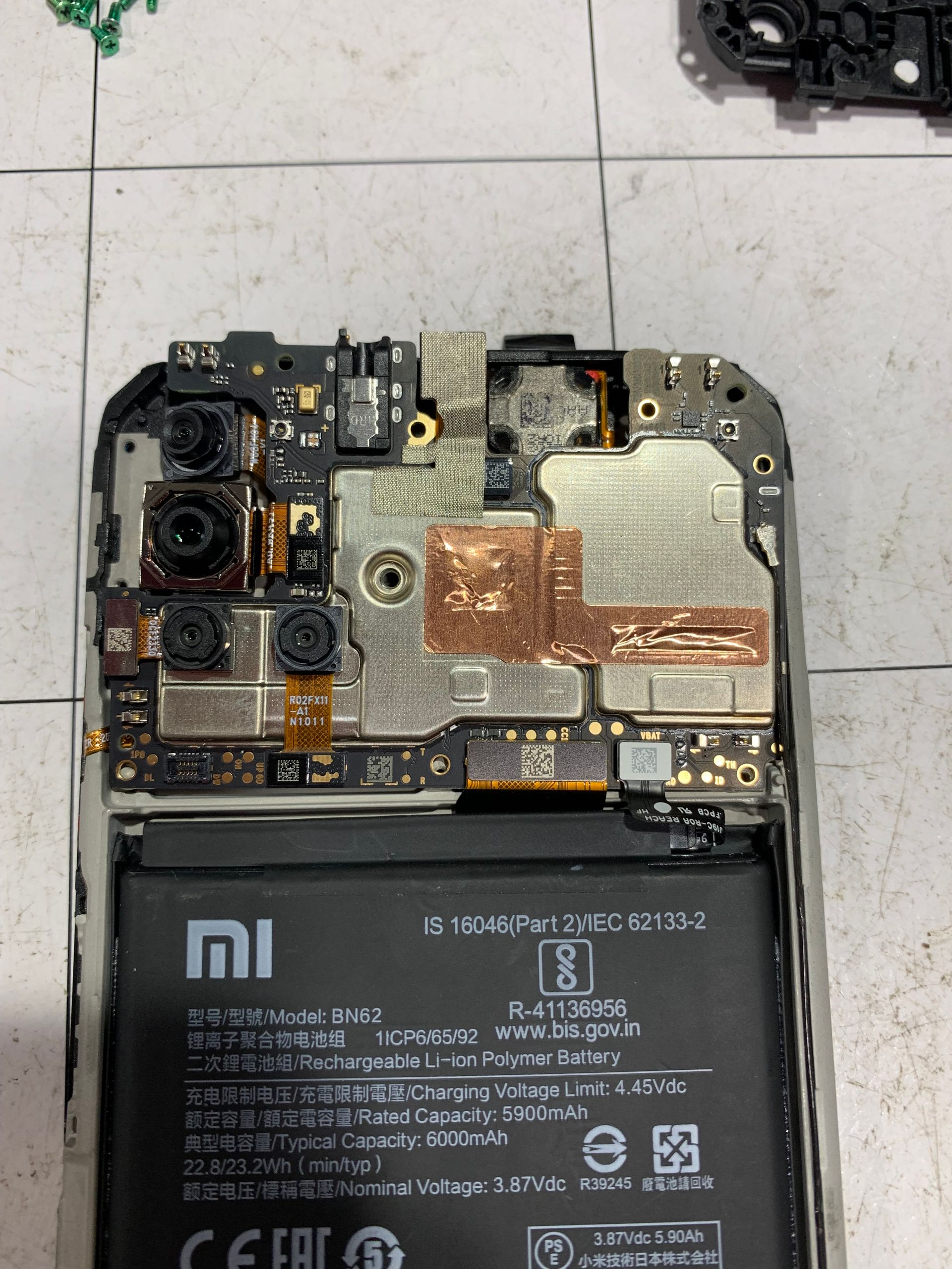 Smartphone ouvert montrant la carte mère interne et la batterie avec blindage argenté