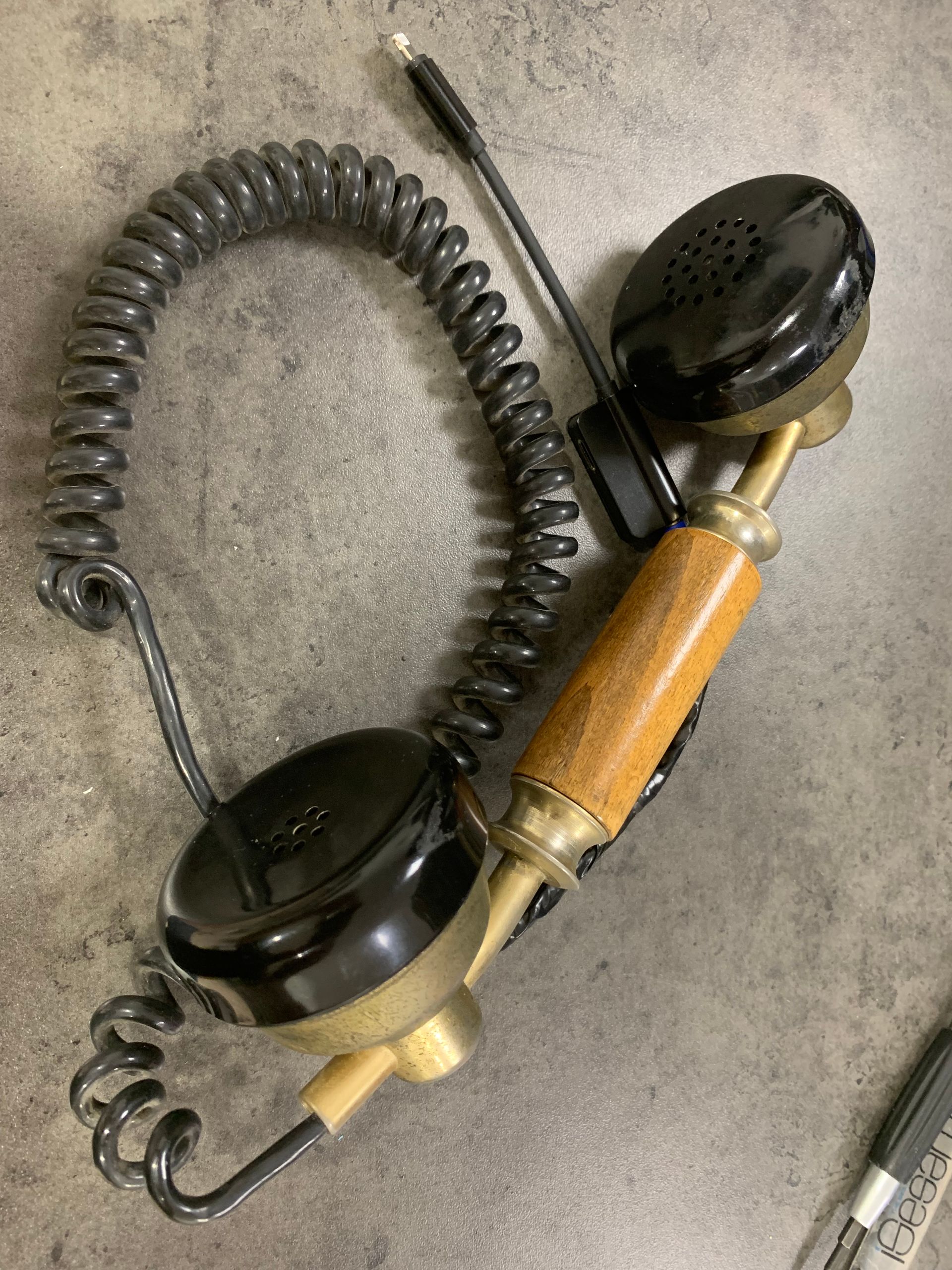 Téléphone vintage noir à cadran avec cordon spiralé sur une surface grise