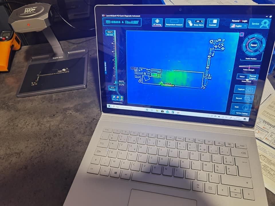Un ordinateur portable affichant un écran bleu de cartographie/analyse est posé sur une table à côté d'un scanner portable.