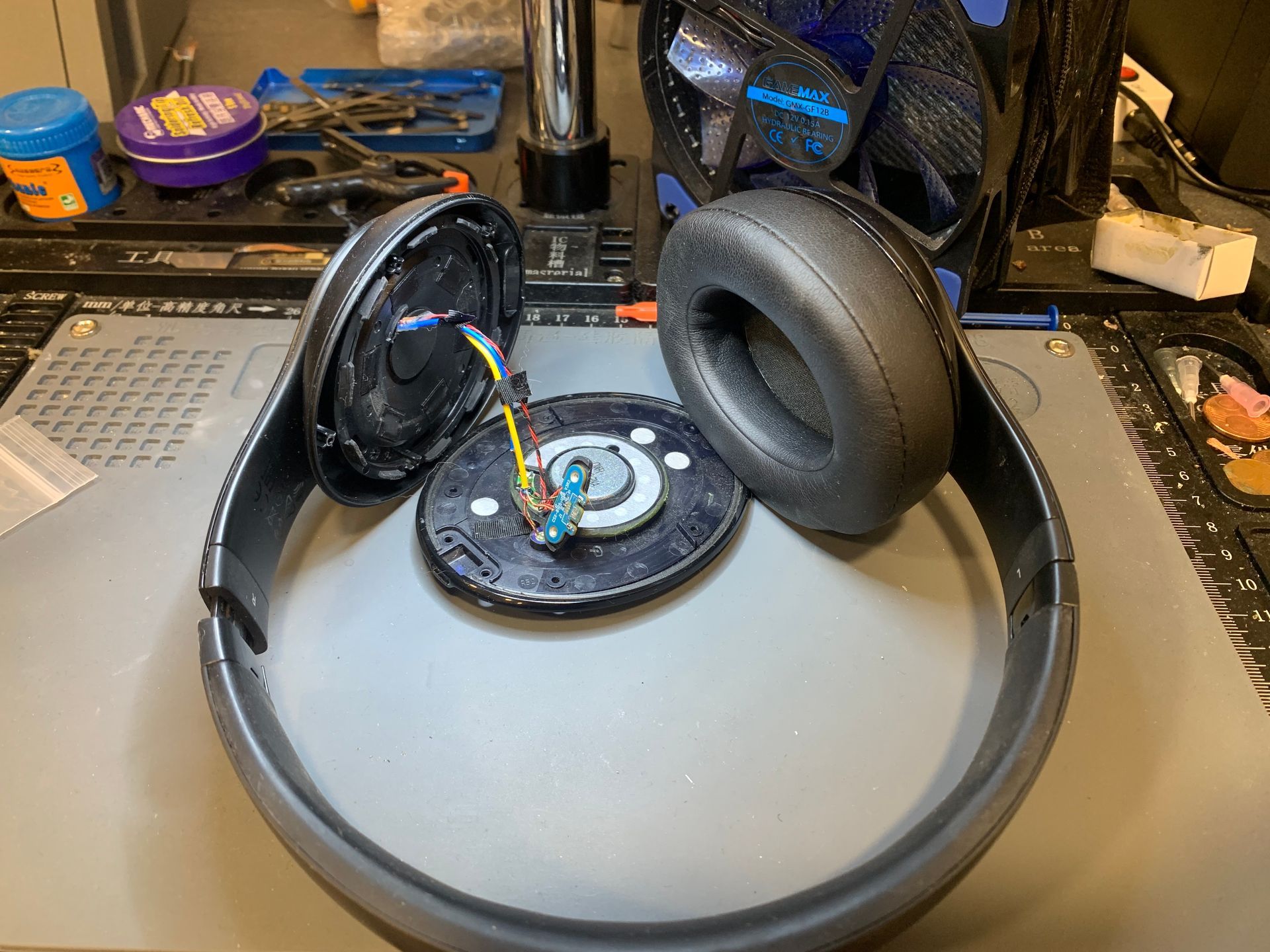 Casque audio noir circum-aural démonté sur un établi, oreillettes et arceau apparents