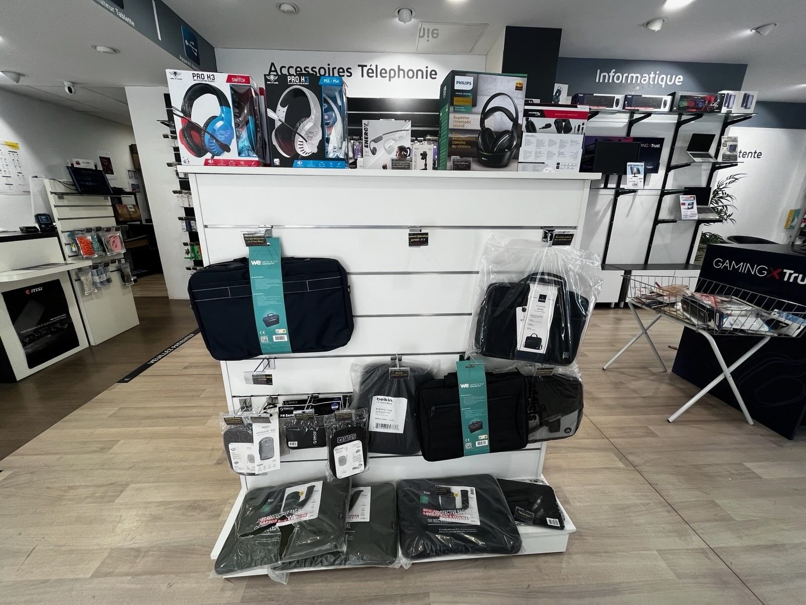 Présentation de bagages et sacs de voyage noirs et turquoise dans un rayon d'un magasin de télécommunications