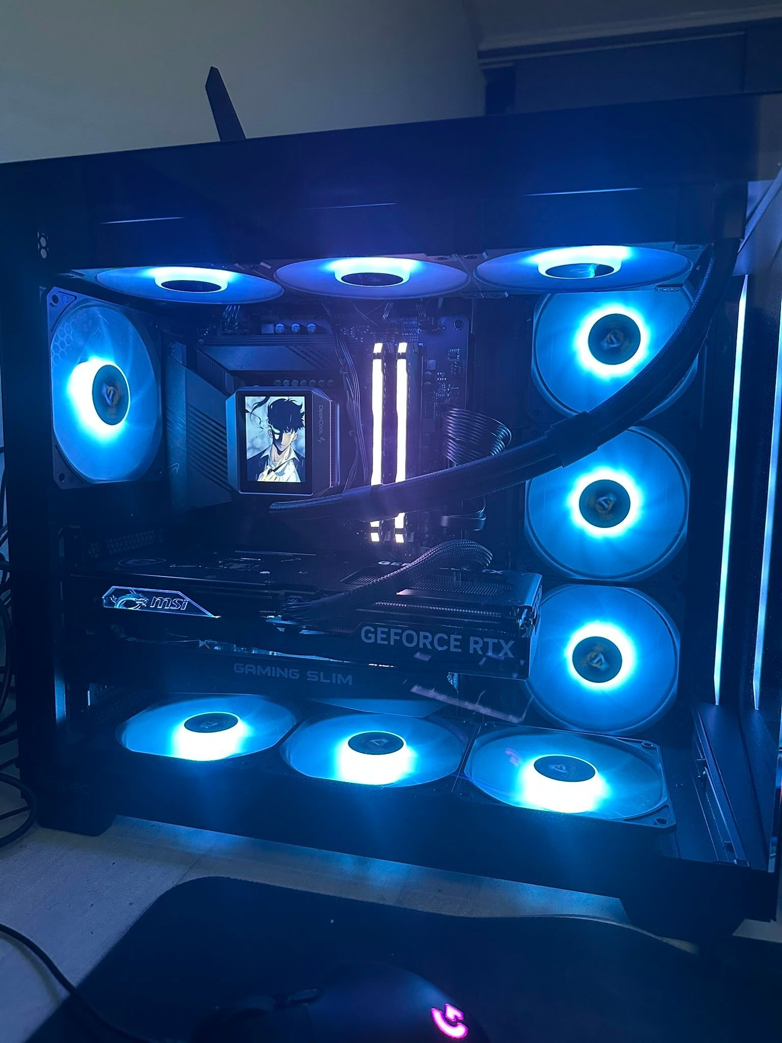 PC de jeu rétroéclairé en bleu avec plusieurs ventilateurs lumineux et composants RGB à l'intérieur d'un boîtier noir
