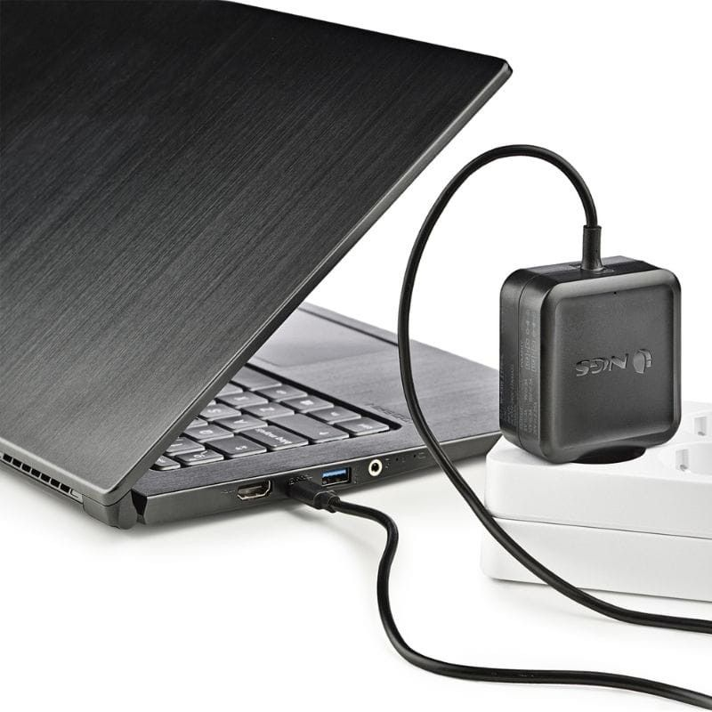 Ordinateur portable connecté à un adaptateur de charge noir sur une surface blanche.