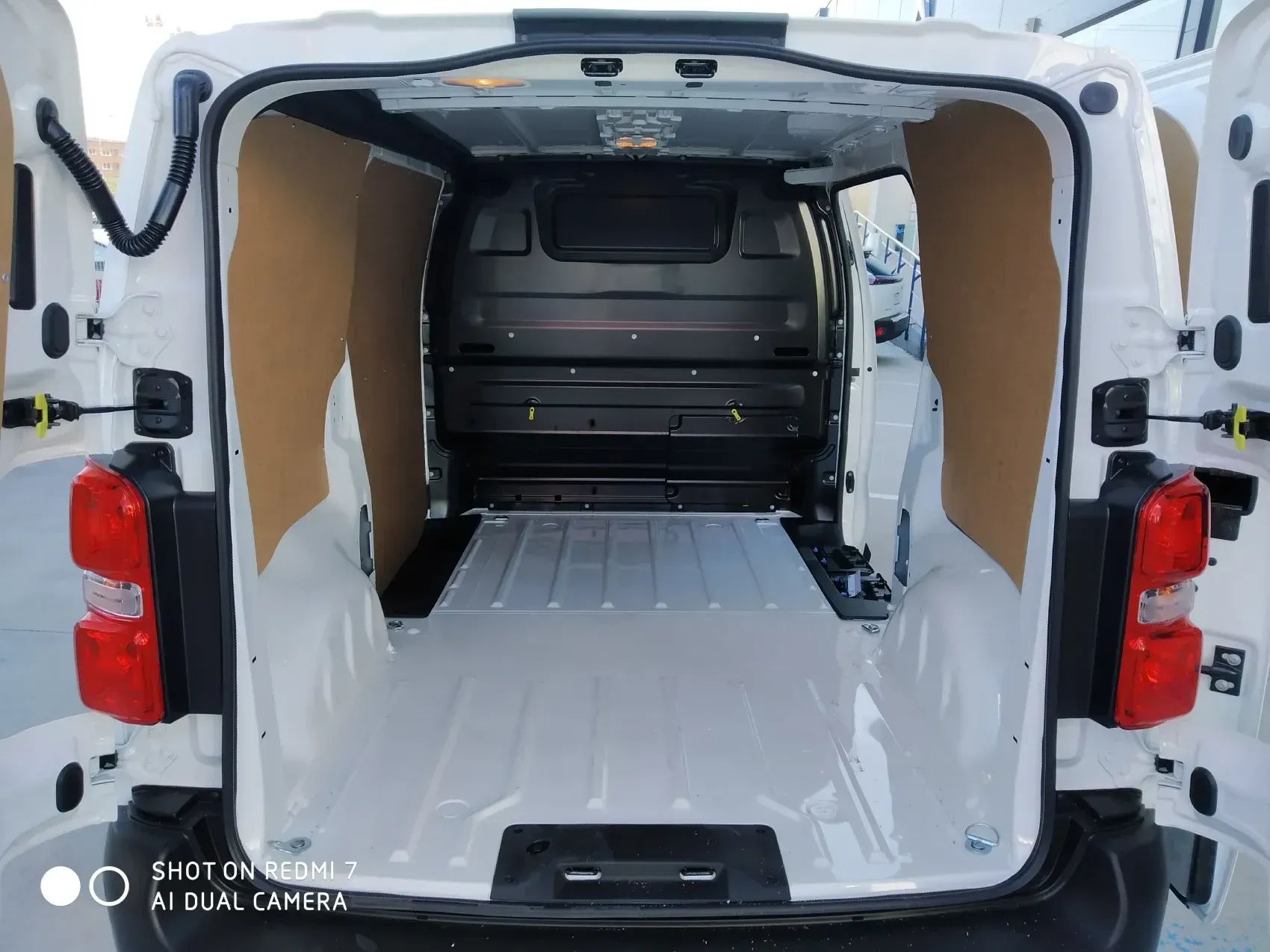 Interior de camioneta de carga blanca vacía con paneles laterales marrones y piso blanco.