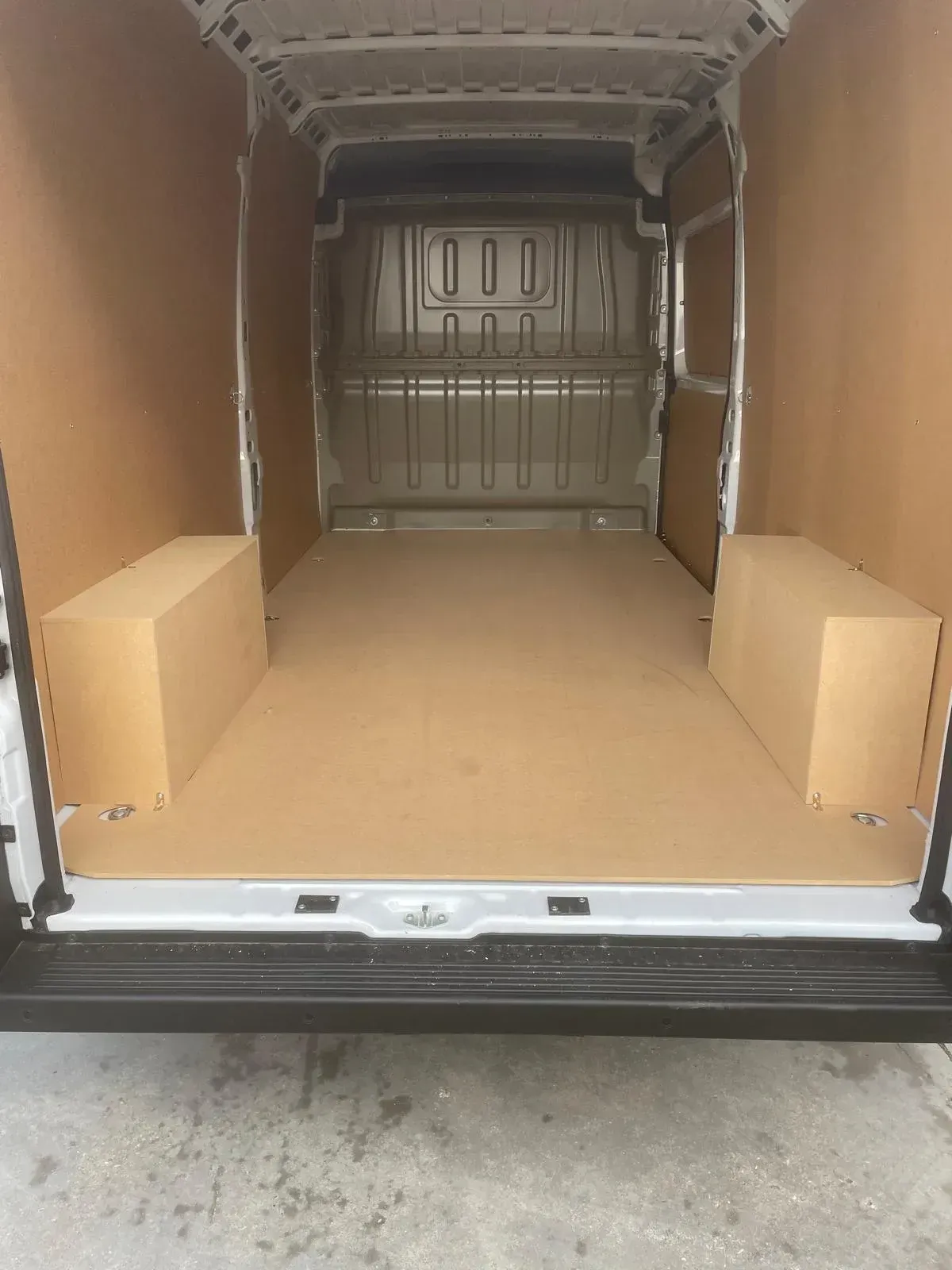 Interior de camioneta de carga vacía con paneles marrones, piso y dos cajas laterales.