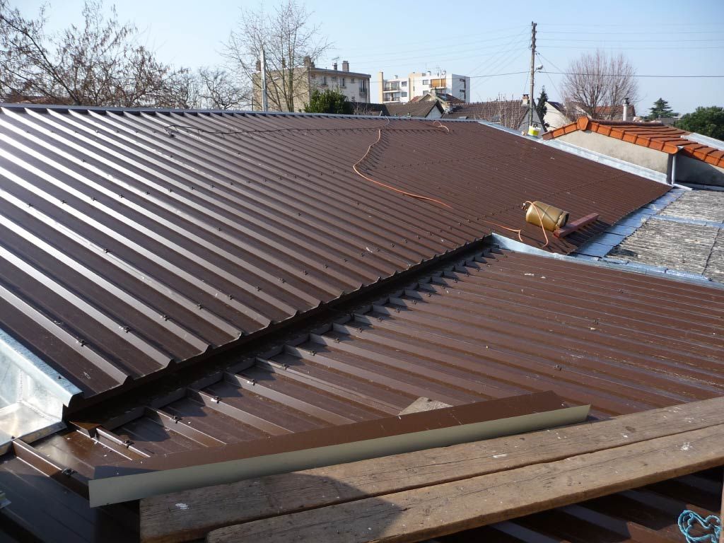 Toiture métallique brune en construction, avec joints et matériaux visibles au premier plan.