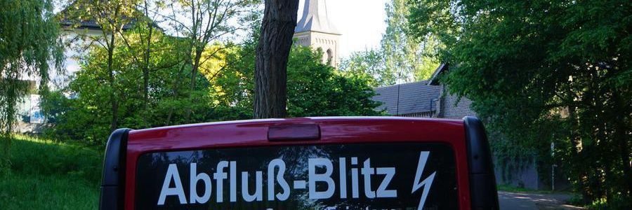 Ein roter Lieferwagen mit einem Schild auf der Rückseite, auf dem steht „Abfluß-Blitz“