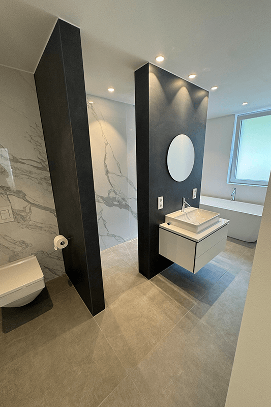 Modernes Badezimmer mit dunklen Akzentwänden, Marmordusche, schwebendem Waschtisch und Toilette.