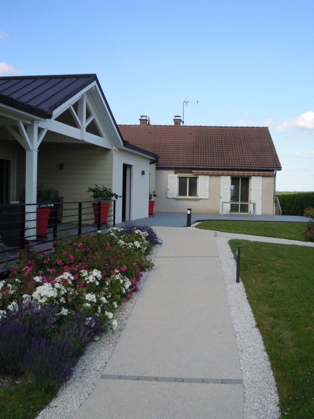 Un chemin pavé mène à une maison bordée de fleurs et d'une pelouse.