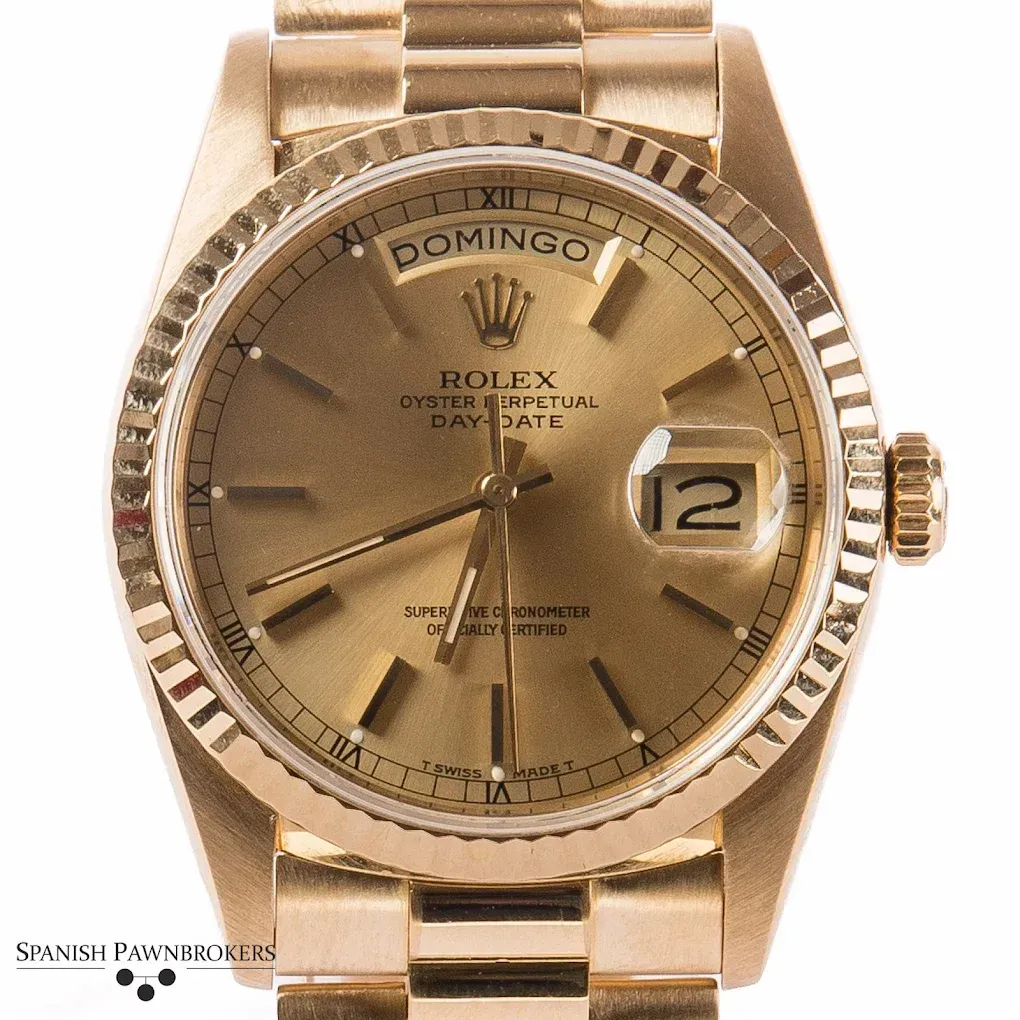 Reloj Rolex Day-Date de oro con bisel estriado y esfera color champán, que marca las 12:10.