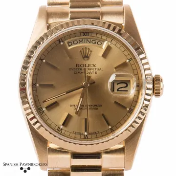 Reloj Rolex Day-Date de oro con bisel estriado y esfera color champán, que marca las 12:10.