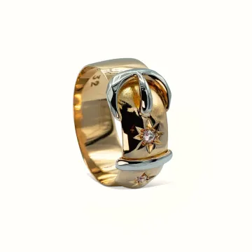Anillo de oro y plata con diseño de mariposa y pequeños detalles de estrellas sobre fondo blanco.