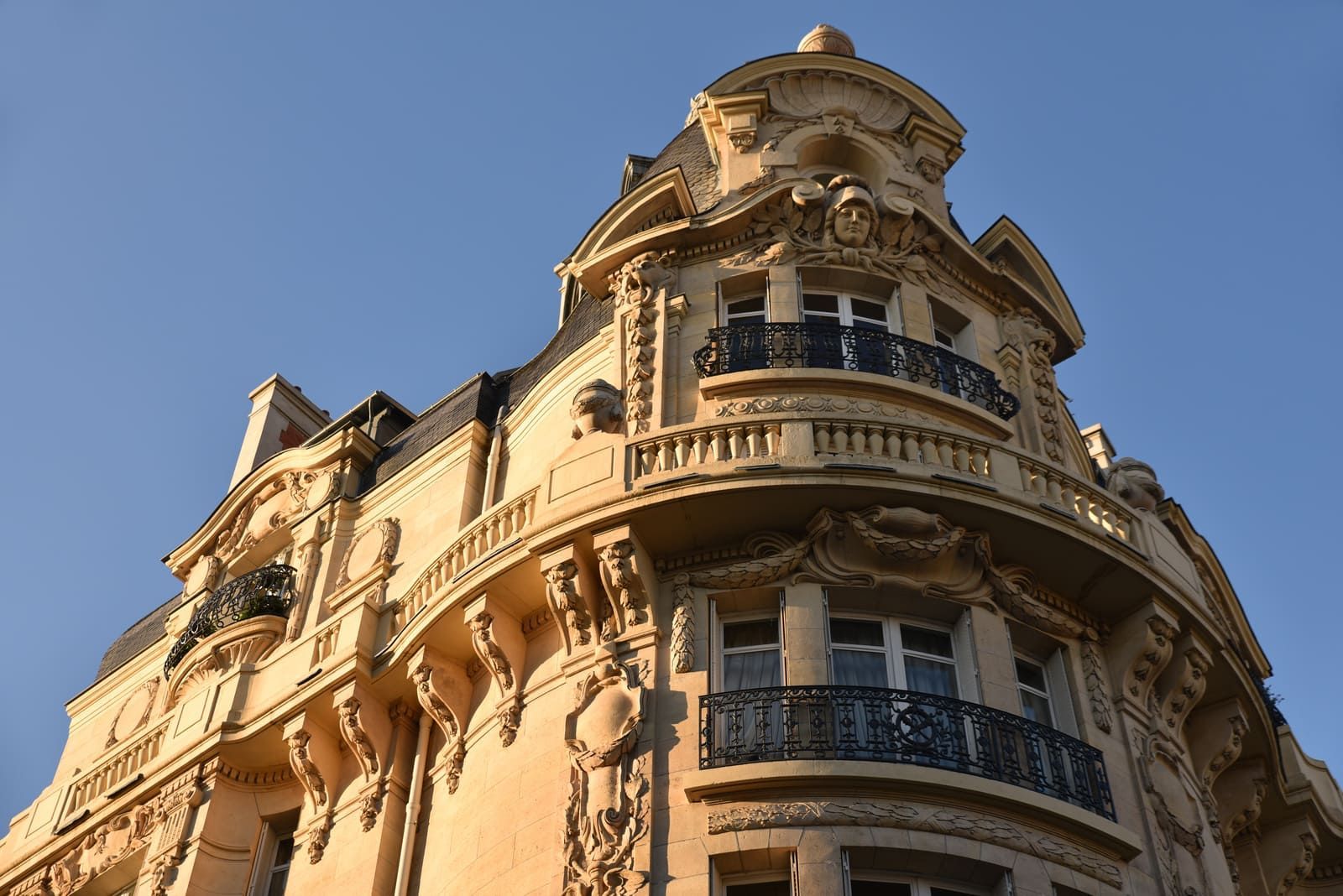 Haut d'un batîment haussmannien avec des balcons en pierre et fer forgé