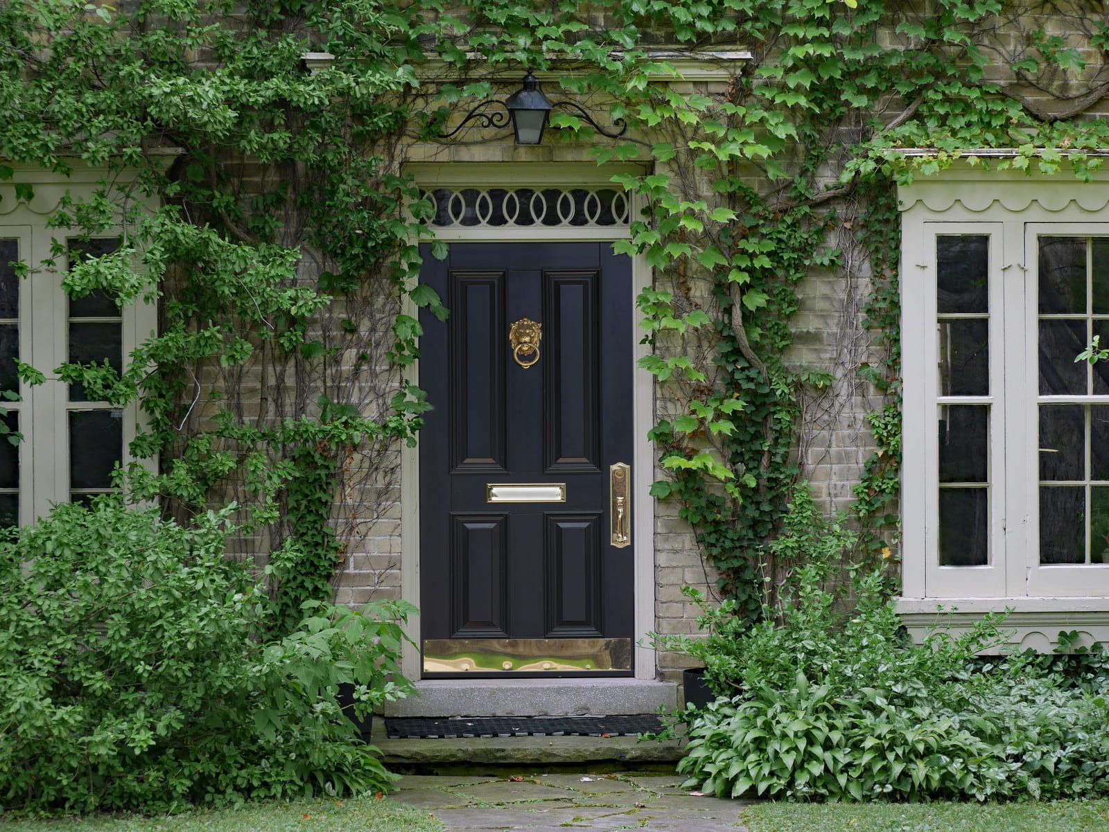 Porte d'entrée style ancien d'une maison avec de la vigne vierge.