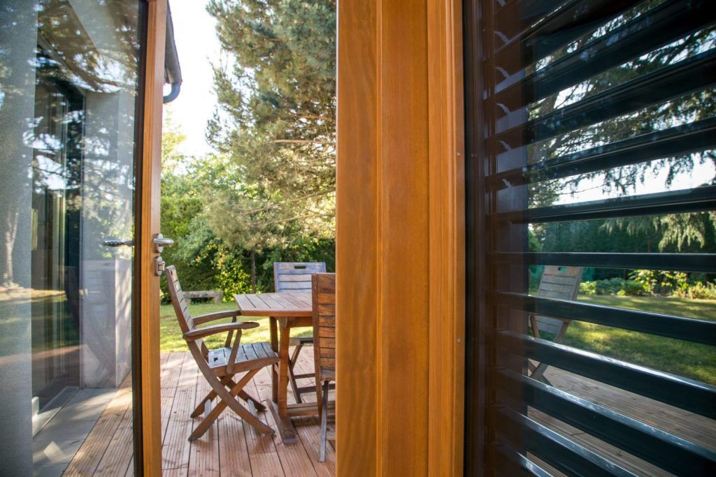 Gros plan sur une fenêtre mixte ouverte vers une table et des chaises sur une terrasse.