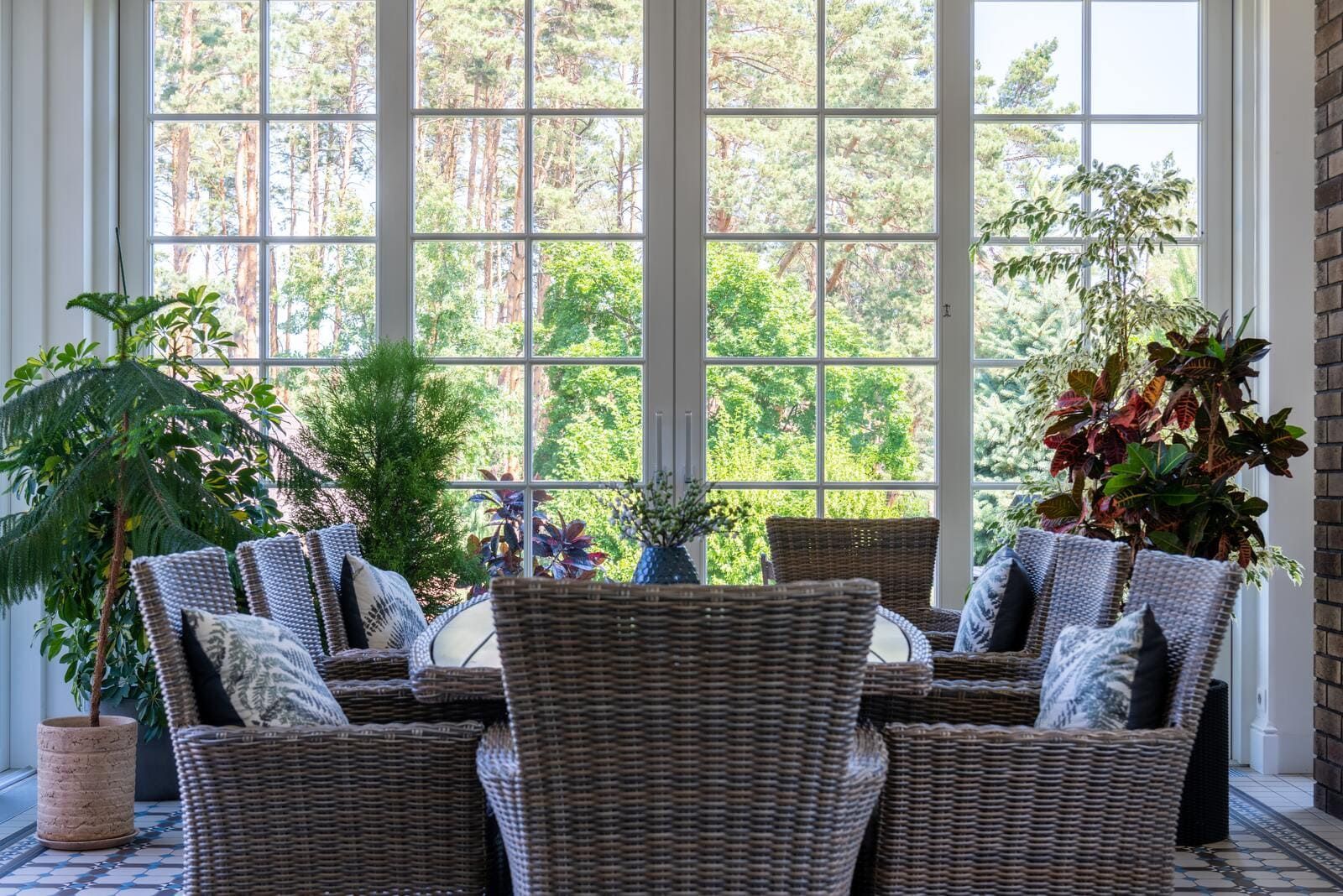 Salon avec des chaises, une tables et des plantes et une grande porte-fenêtre en PVC