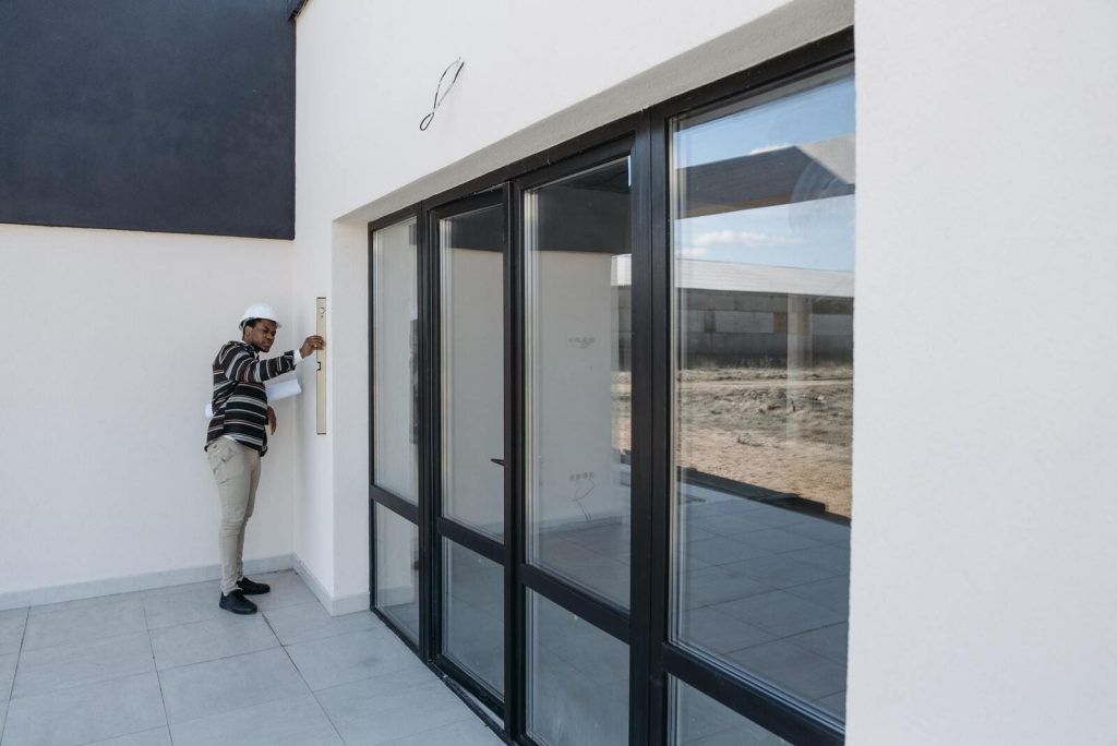 Installateur de porte-fenêtre qui vérifie le niveau par rapport au mur de la maison.