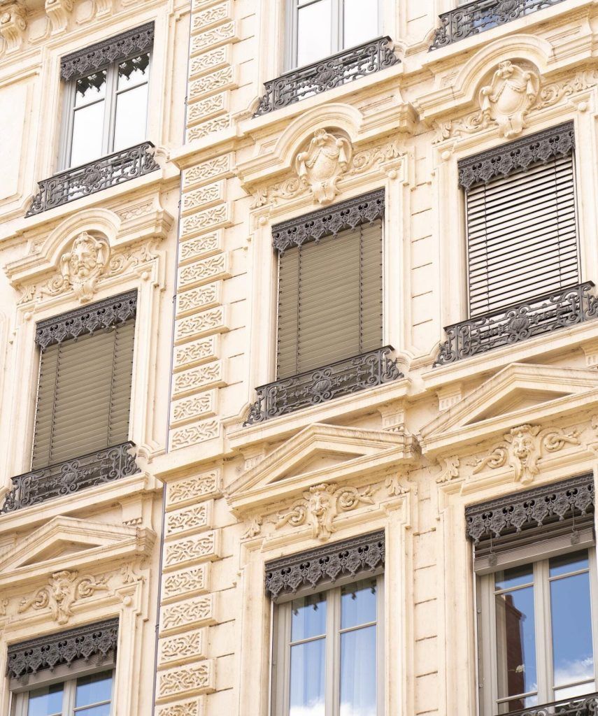 Gros plan sur une façade de batîment avec des fenêtres haussmanniennes