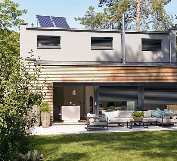 Volets roulants électriques sur des baies vitrées d'une maison au bardage en bois