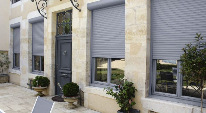 Volets roulants sur quatre fenêtres d'une maison en pierre