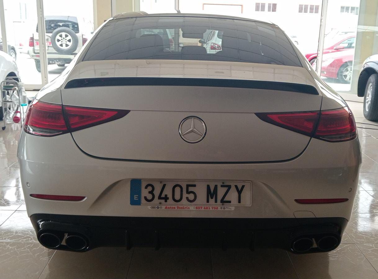 Vista trasera de un sedán Mercedes blanco estacionado en un garaje, con la matrícula 3405 MZY visible.