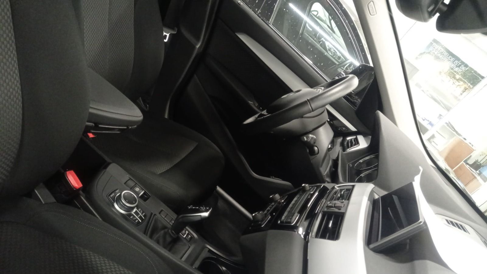 Interior del coche con asientos, consola central y salpicadero negros, visto desde el lado del pasajero.