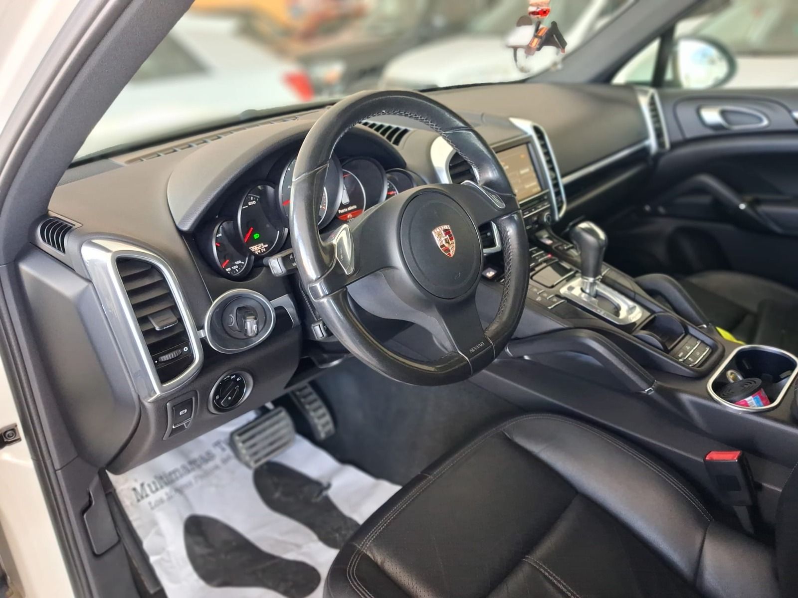 Interior de un deportivo Porsche negro, donde se aprecian el volante, el salpicadero y los asientos delanteros.